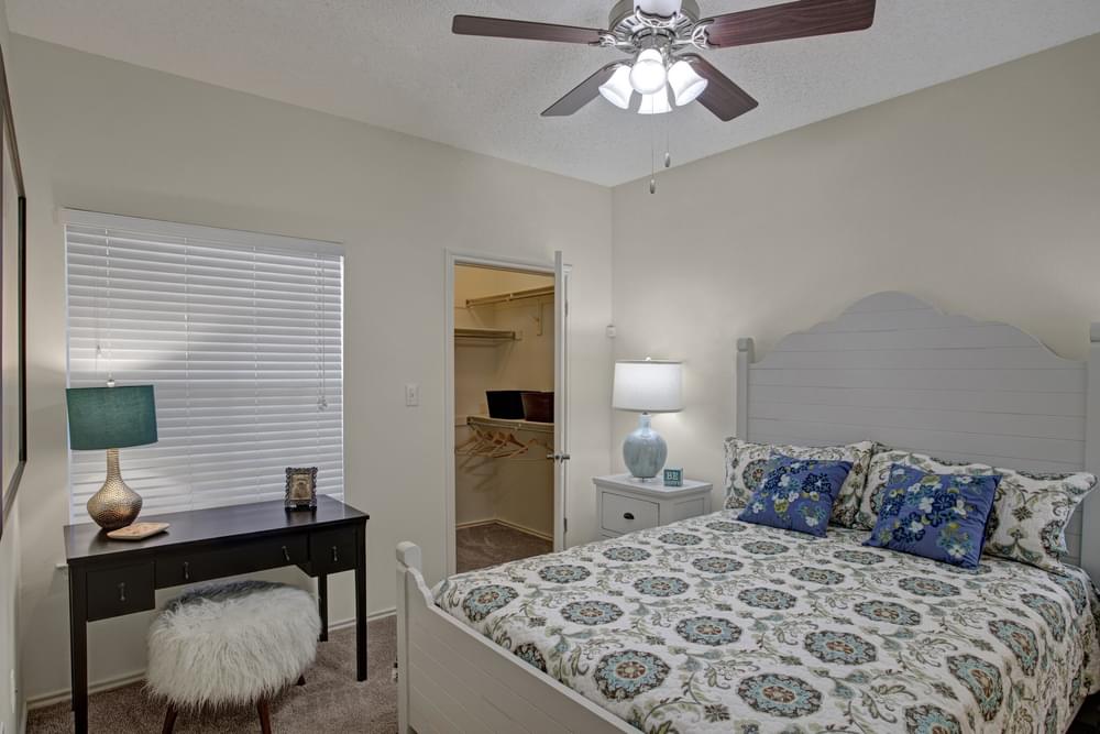 Arbors at Wolf Pen Creek Apartments whimsical bedroom with large bed, desk and office chair, walk-in closet, and ceiling fan