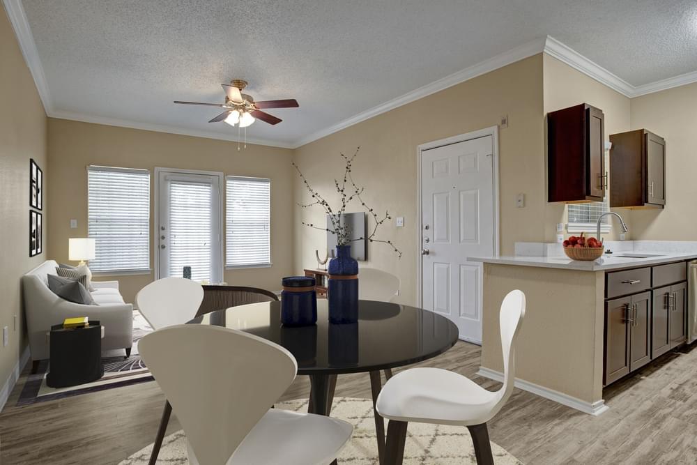 Arbors at Wolf Pen Creek Apartments Cozy living room with a sectional sofa, round tables, ceiling fan, and dining area.