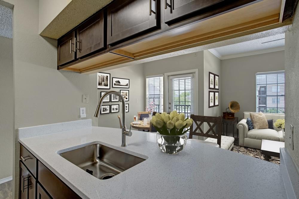 Modern kitchen with dark wood cabinets, stainless steel appliances, white countertops, and decorative wall art.