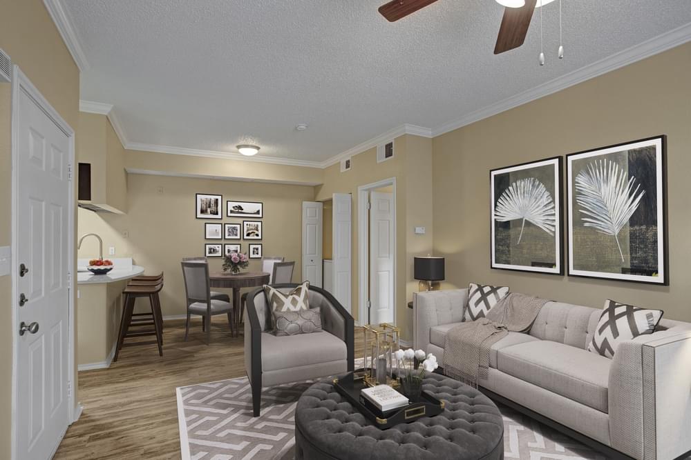 Arbors at Wolf Pen Creek Apartments Cozy living room with a sectional sofa, round tables, ceiling fan, and dining area.