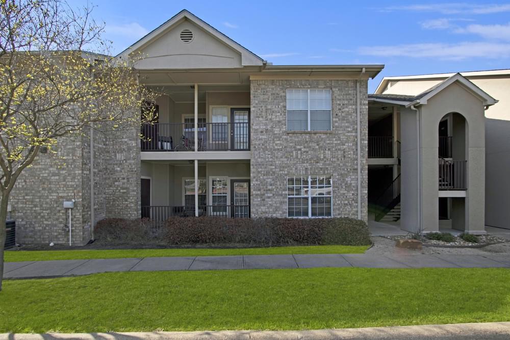 The Arbors at Wolf Pen Creek apartments Two-story brick apartment building with balconies and a grassy front yard.