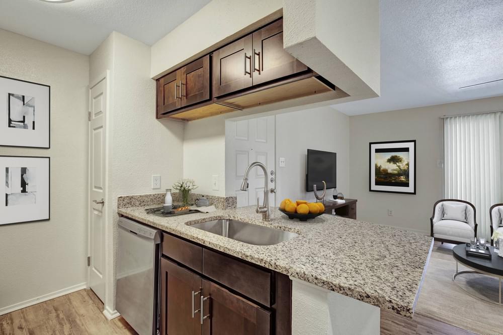 Village Green apartments Kitchen with large granite counters, wooden cabinets, dish washer, sink and breakfast bar for barstools.