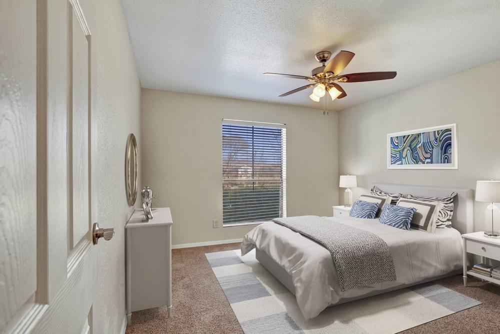 Village Green apartments Large bedroom with carpet floor, fan, and window