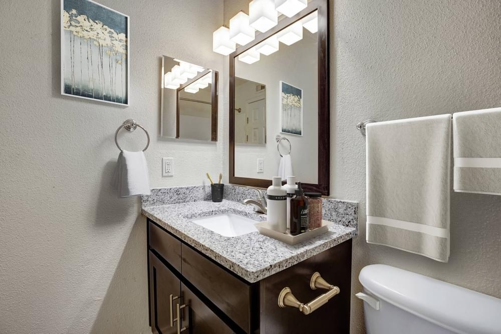 Village Green apartments Bathroom granite sink with two large mirrors on wall
