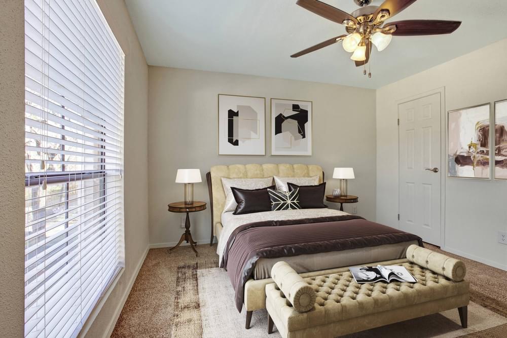 Village Green apartments Spacious bedroom with large window, carpet, and fan.