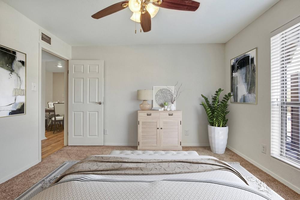 Village Green apartments Spacious bedroom with large window, carpet, and fan.