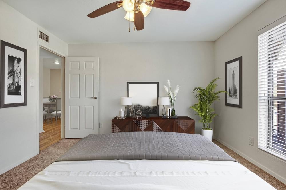 Village Green apartments Spacious bedroom with large window, carpet, and fan.