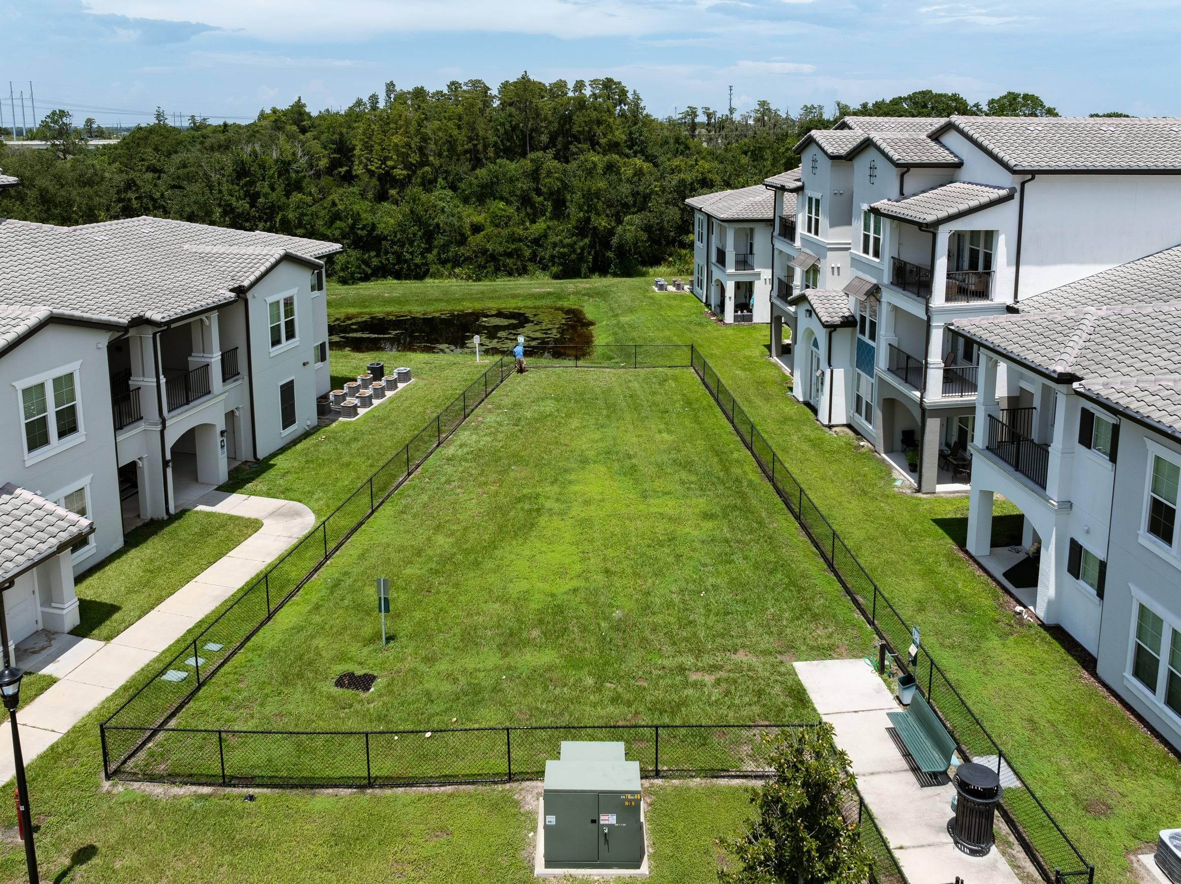 Shadetree Apartments large, fenced on-site dog park with green grass on a sunny day