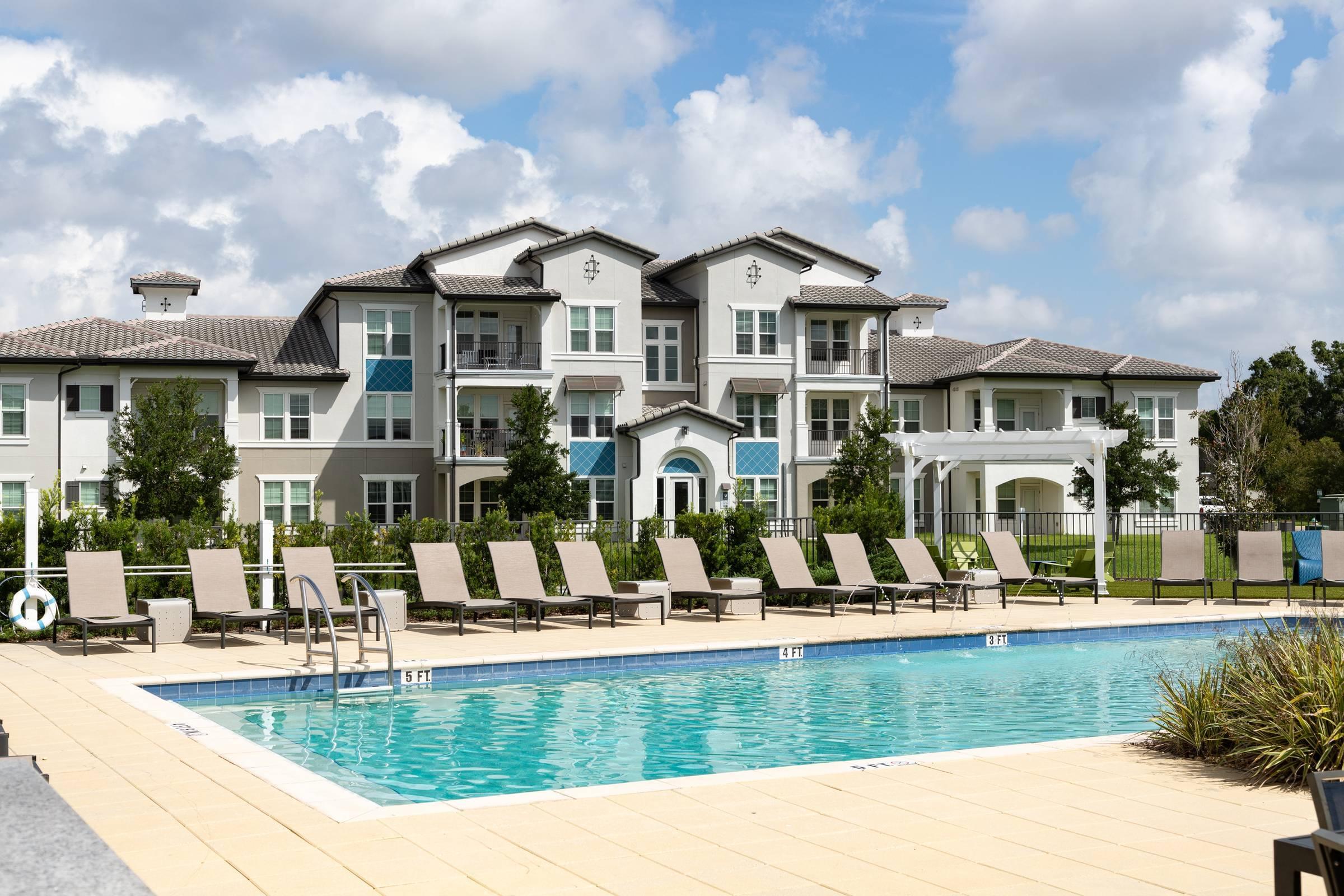 Shadetree Apartments with a sparkling swimming pool and sundeck with lounge chairs
