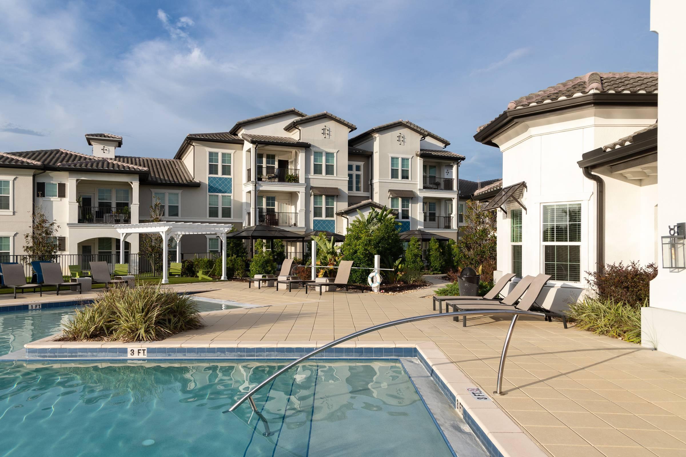 Shadetree Apartments with a sparkling swimming pool and sundeck with lounge chairs