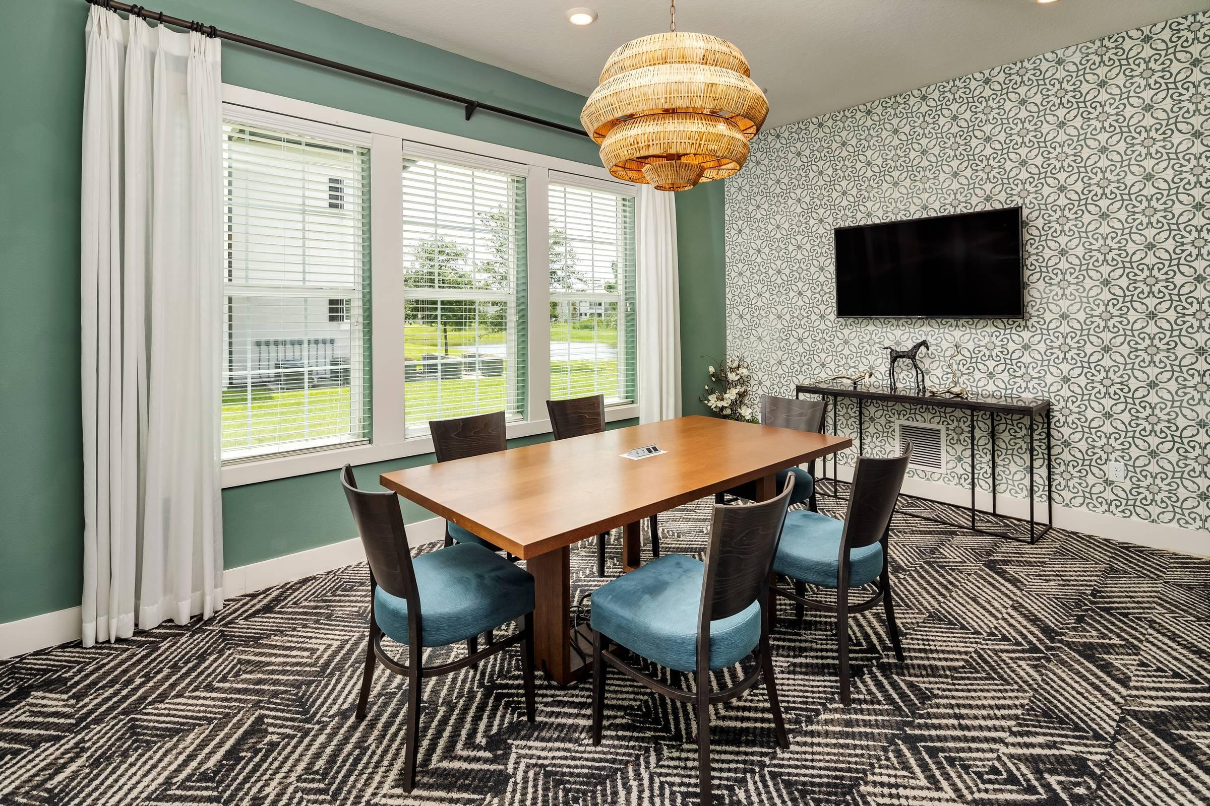 Shadetree Apartments clubhouse dining room with a dining table, chairs, TV, and abundant natural light