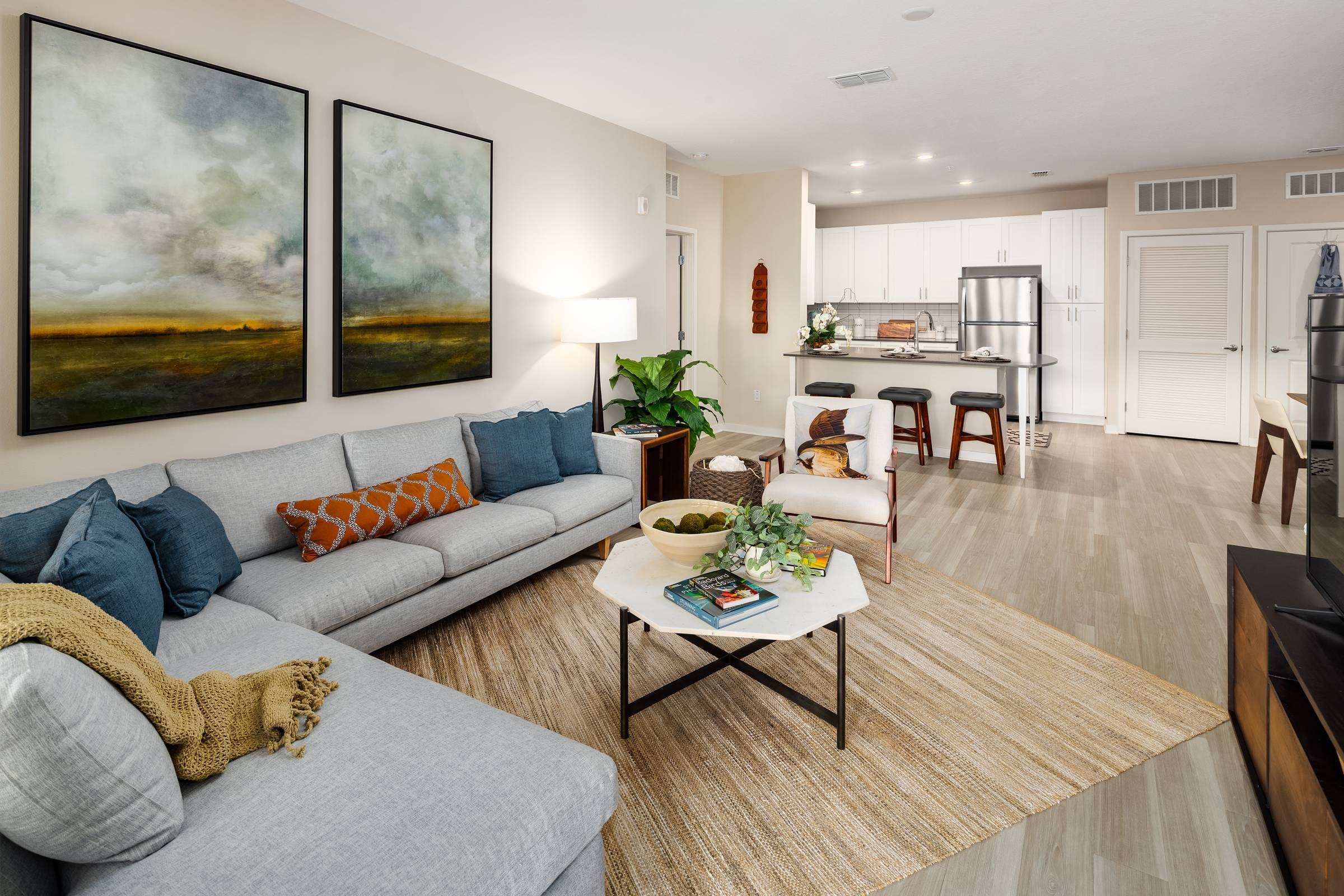 Shadetree Apartments living room with an L-shaped sofa, coffee table, rug, and wall art