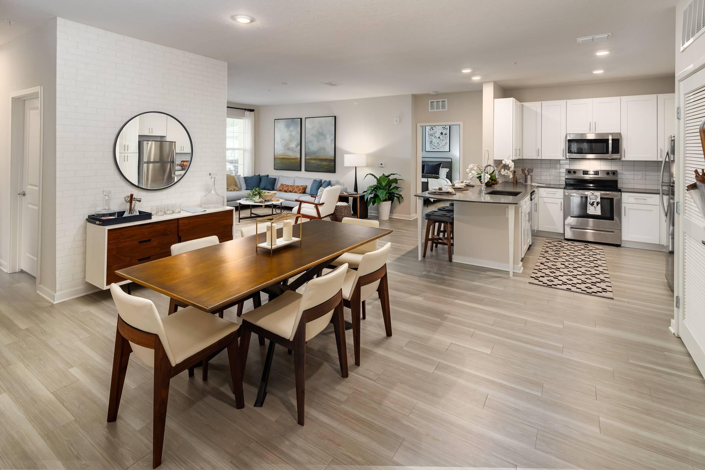 Shadetree Apartments kitchen and dining room with a dining table, chairs, wall mirror, and hardwood-style vinyl plank flooring