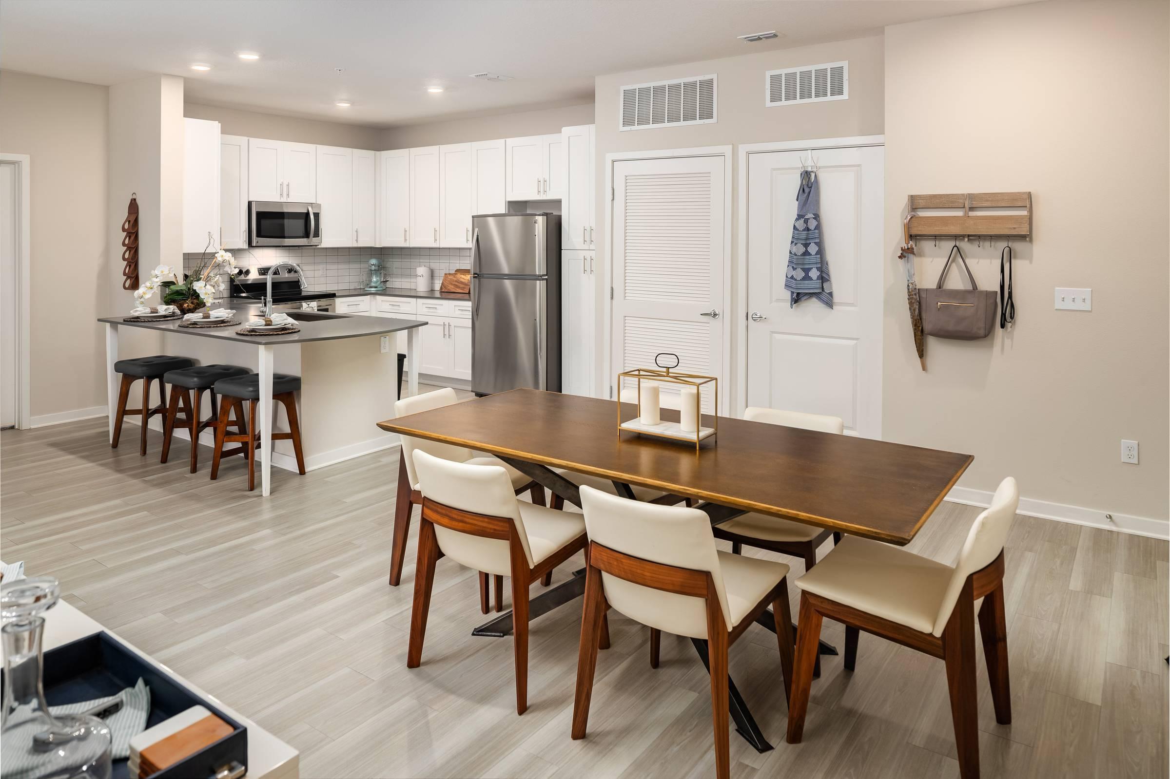 Shadetree Apartments kitchen and dining room with a dining table, chairs, wall mirror, and hardwood-style vinyl plank flooring