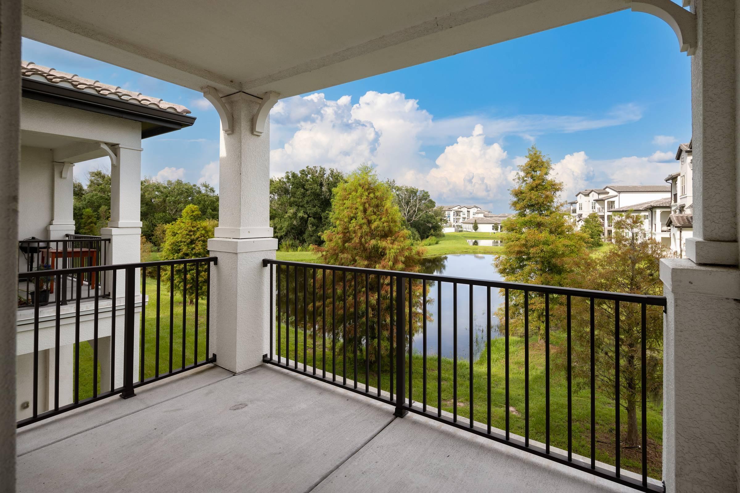 Shadetree Apartments large balcony with a gorgeous view of a small lagoon surrounded by green trees and shubs with a bright blue sky and fluffy white clouds