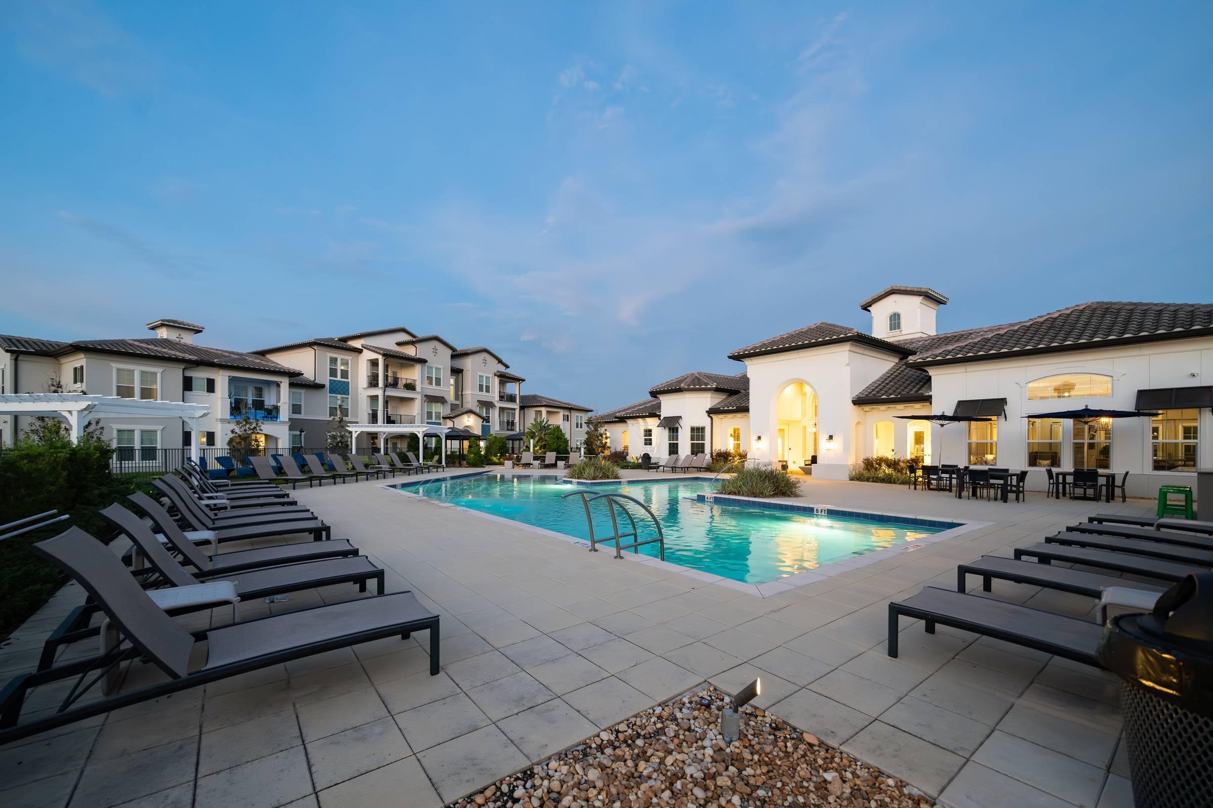 Shadetree Apartments swimming pool at dusk with vibrant lights around the pool deck