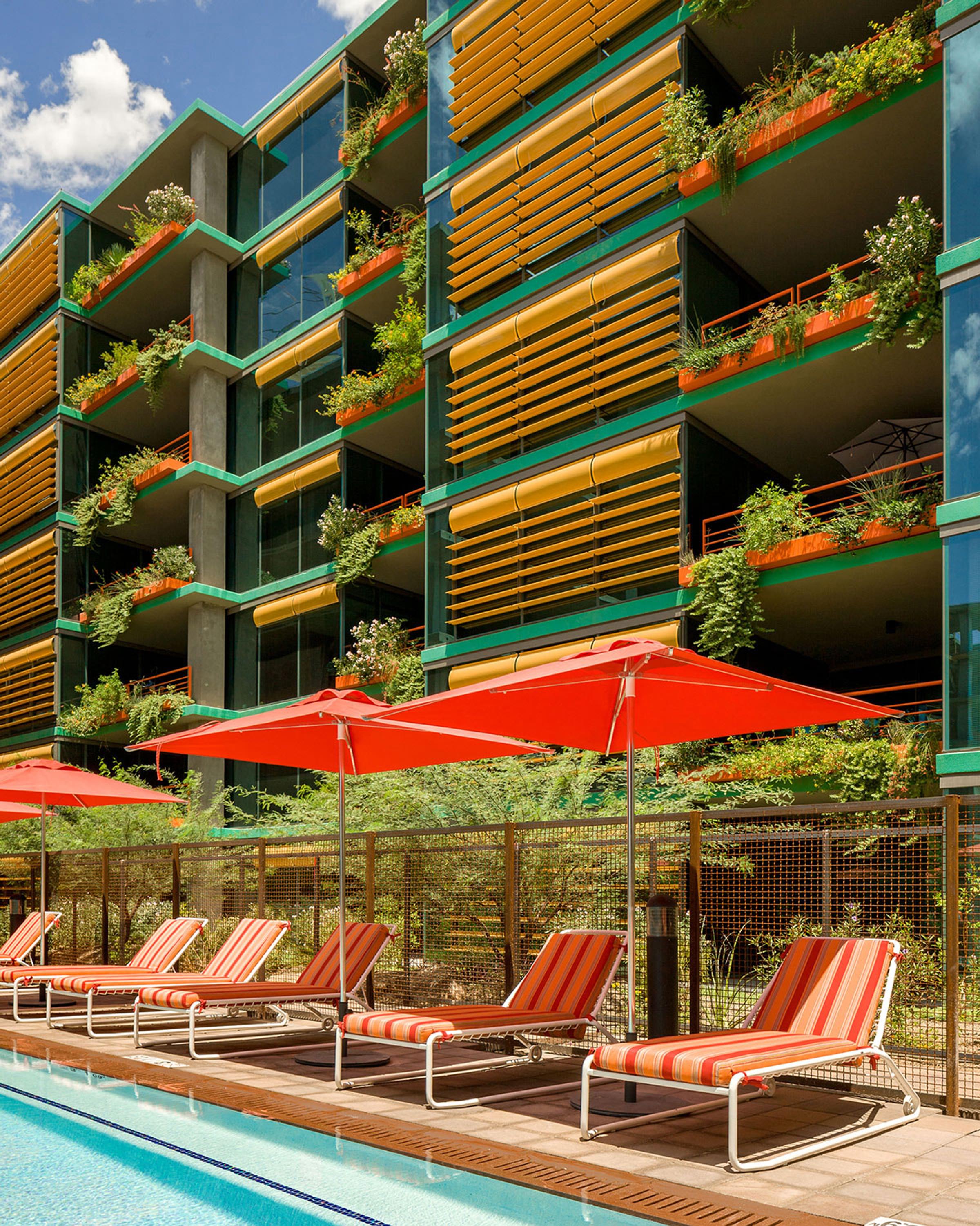Optima Sonoran Village apartments outdoor lounge area with colorful lounge chairs under umbrellas.