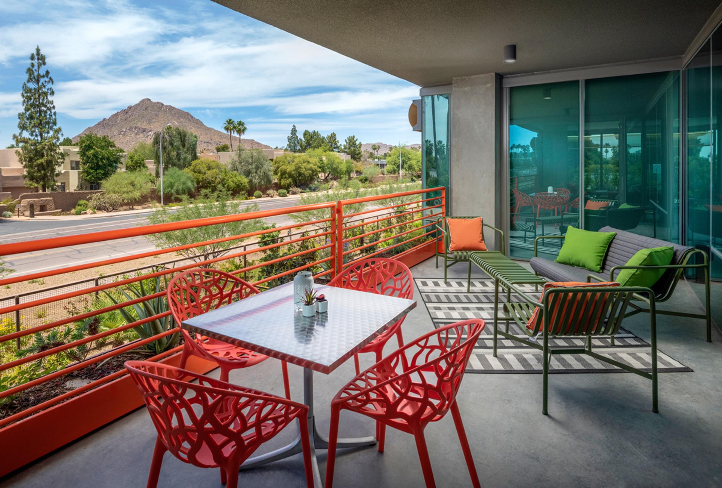 Optima Sonoran Village apartments large balcony with modern colorful patio furniture, and view of mountainous desert landscape.