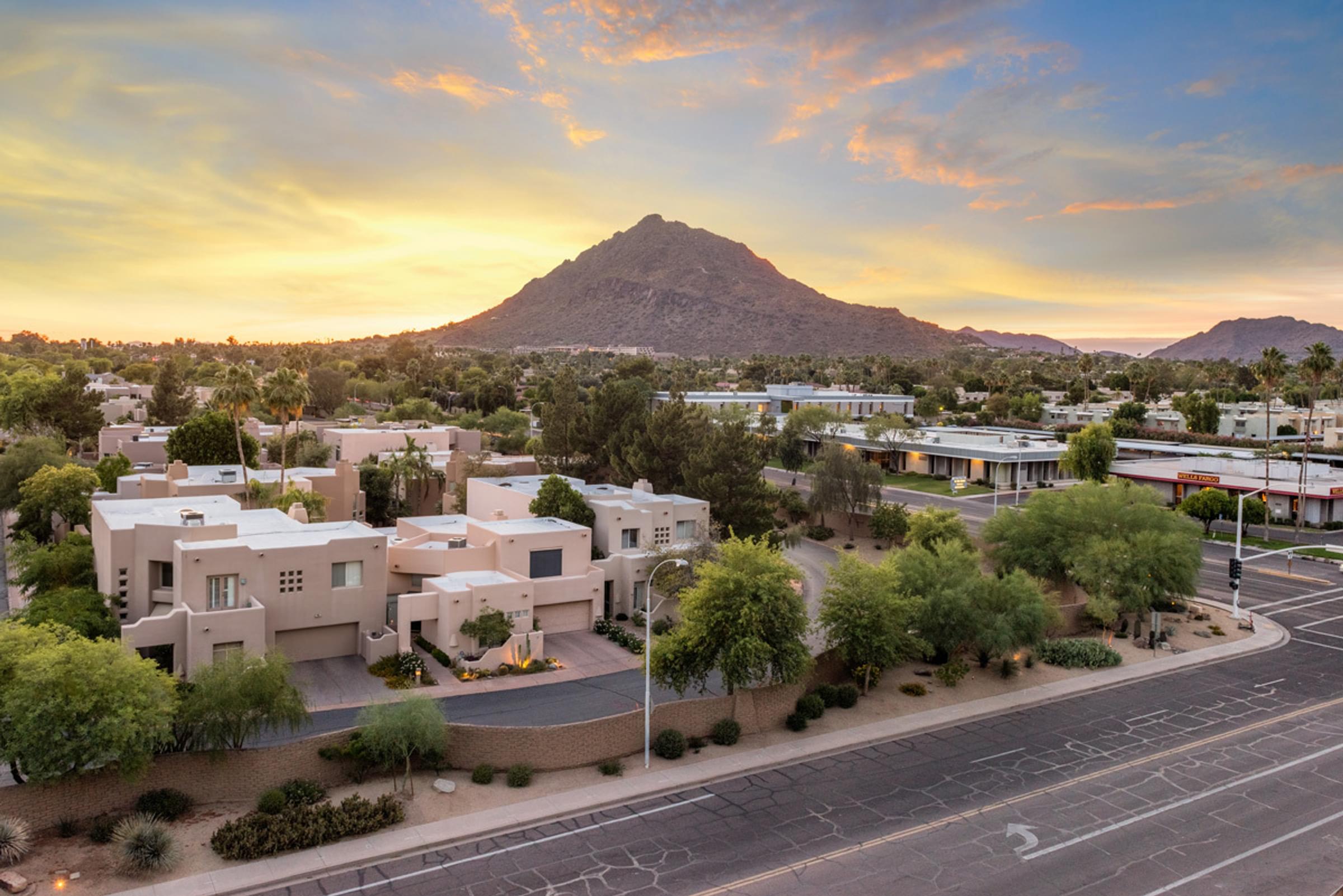 Suburban street with houses and trees at sunset, mountain in the background under a colorful sky taken from Optima Sonoran Village balcony.