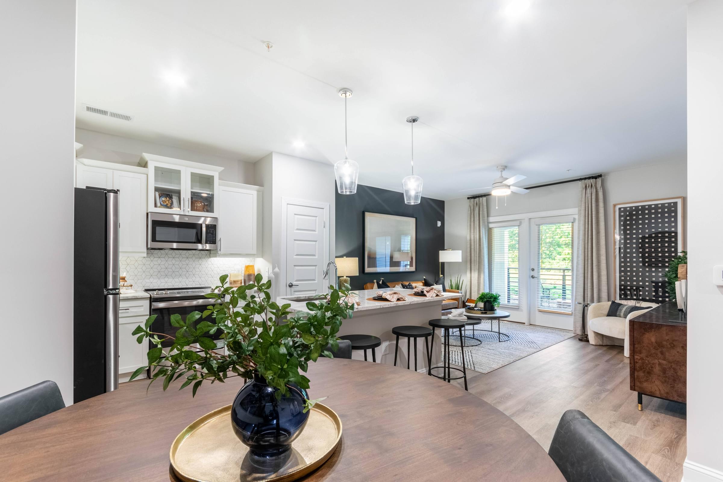 Spacious Dining Area that peeks into the Open Kitchen with White Cabinets and Stainless Steel Appliances