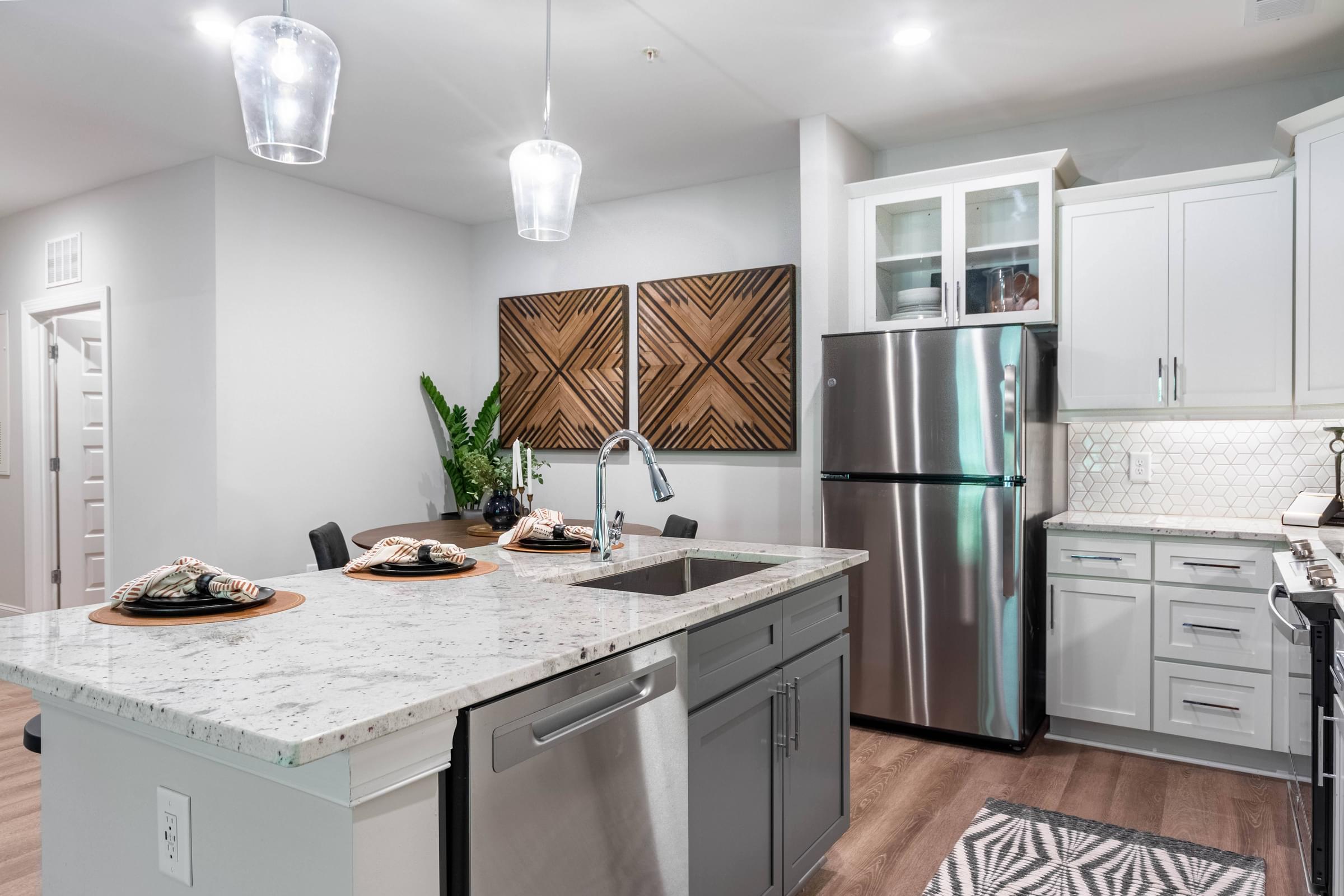 a kitchen with a marble counter top and a stainless steel refrigerator