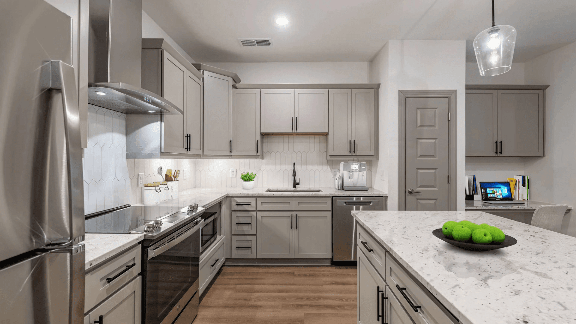 A modern kitchen with a stainless steel refrigerator and wooden floors.