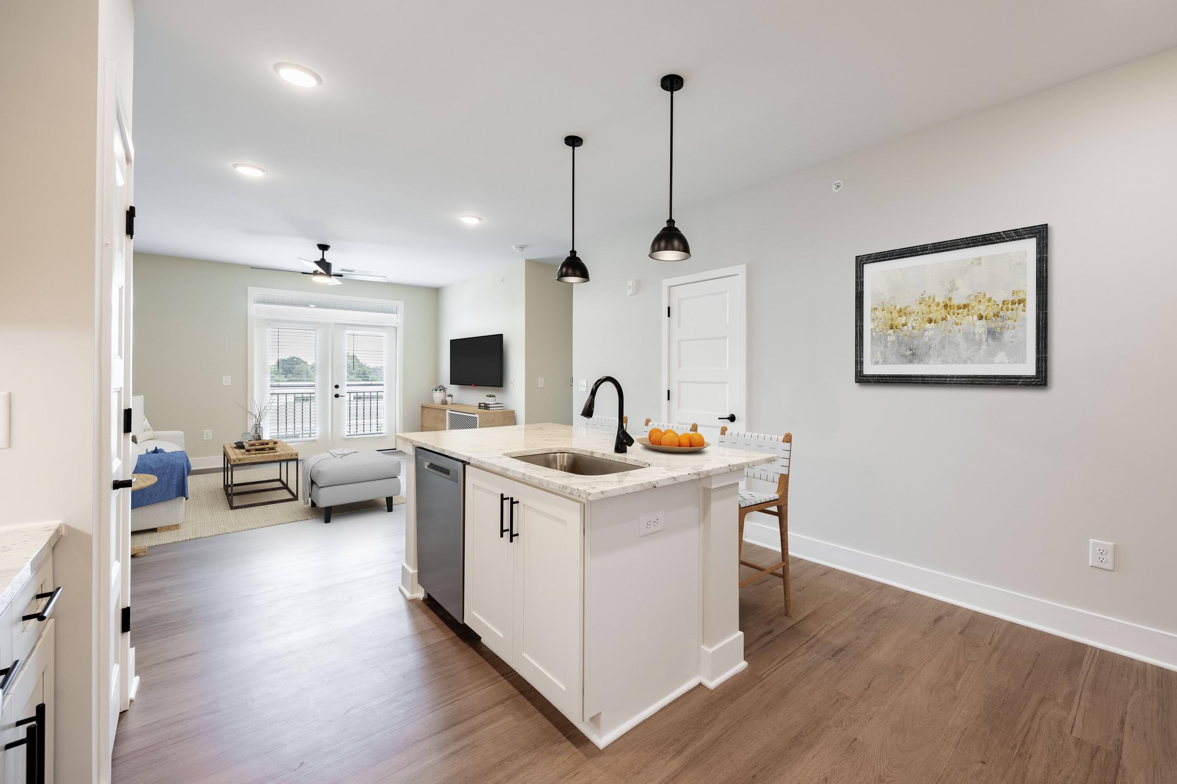 an open kitchen and living room with white cabinets and a counter top