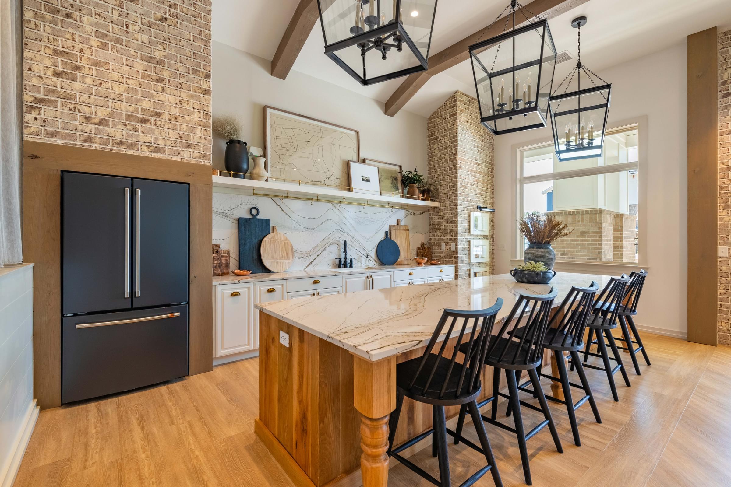 the kitchen has a large island with chairs and a black refrigerator