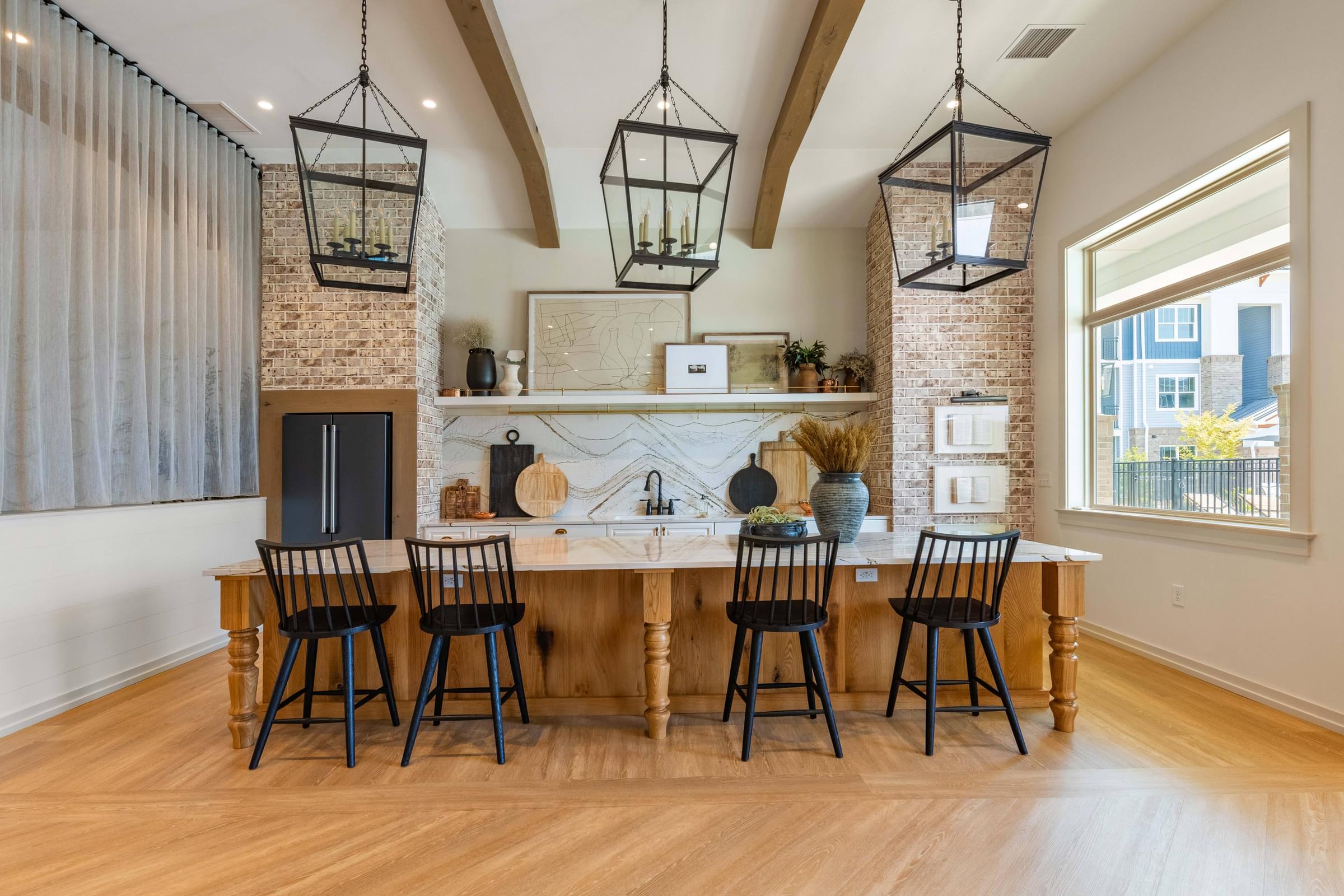 A kitchen with a wooden table and chairs, a brick fireplace, and pendant lights.