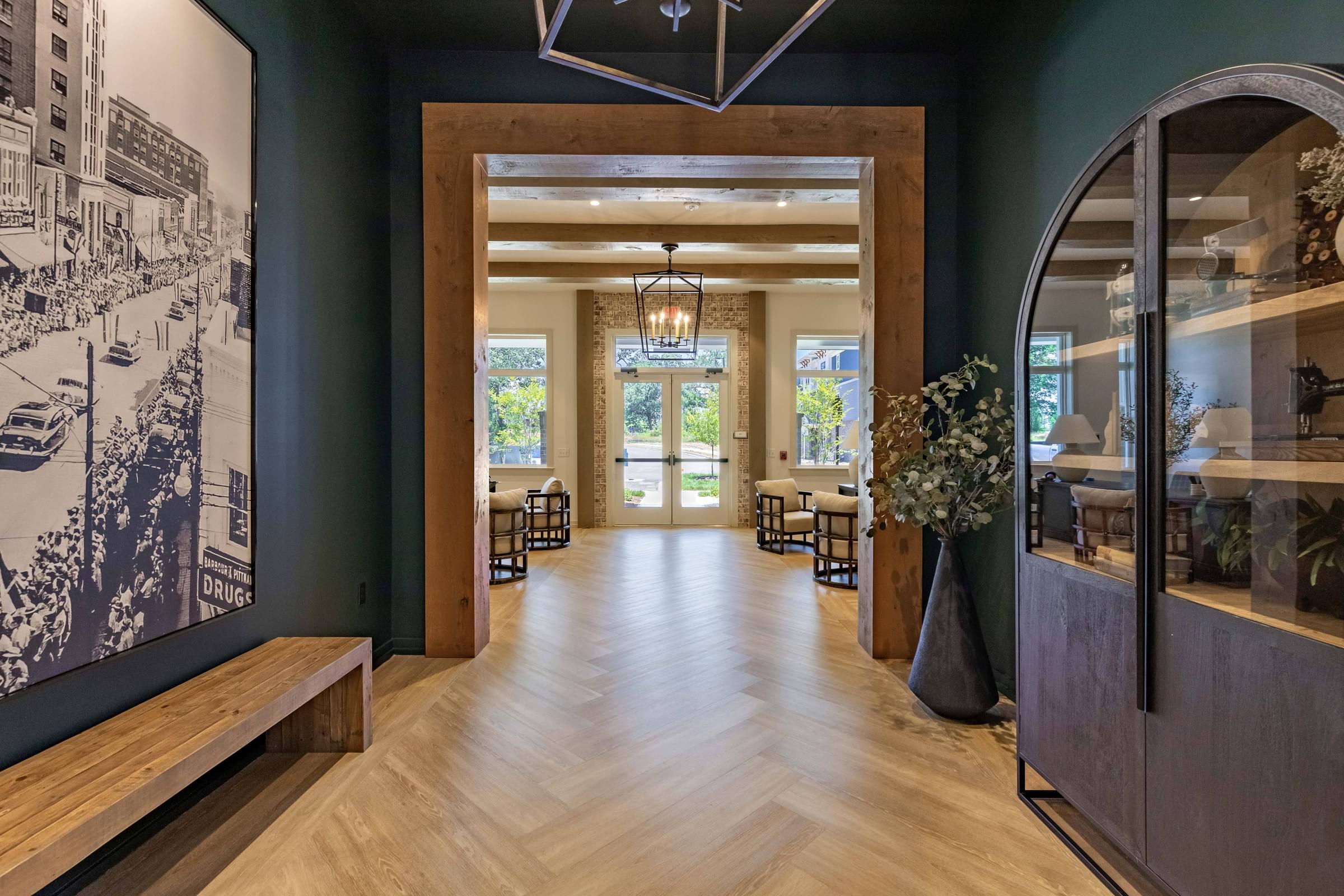 A long hallway with a bench on the left and a vase of flowers on the right.