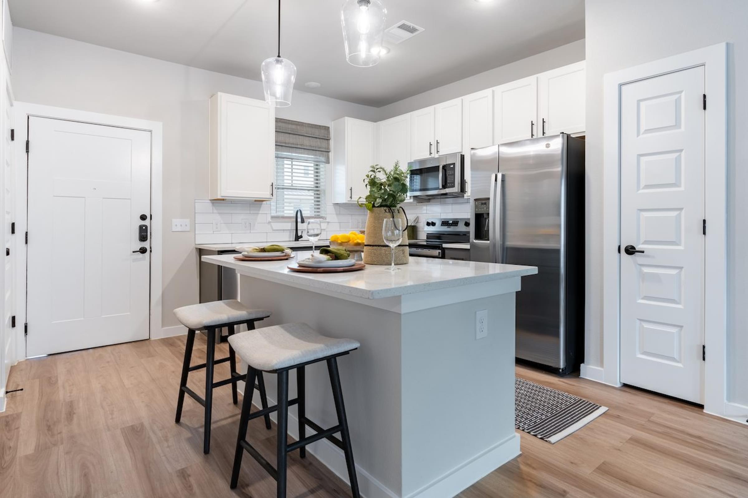 A kitchen with a white island and bar stools.