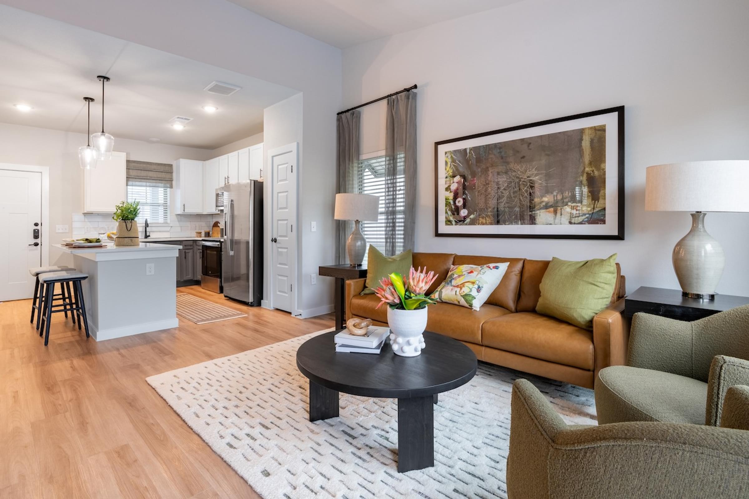 A modern living room with a brown couch, a coffee table, and a painting on the wall.