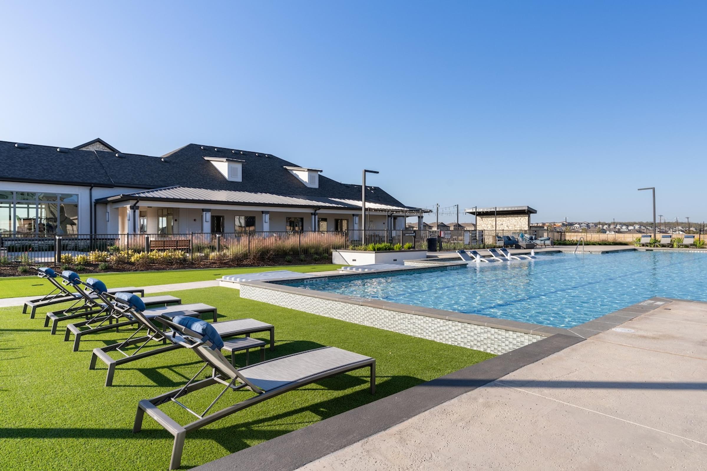 A pool with sun loungers in front of a building.