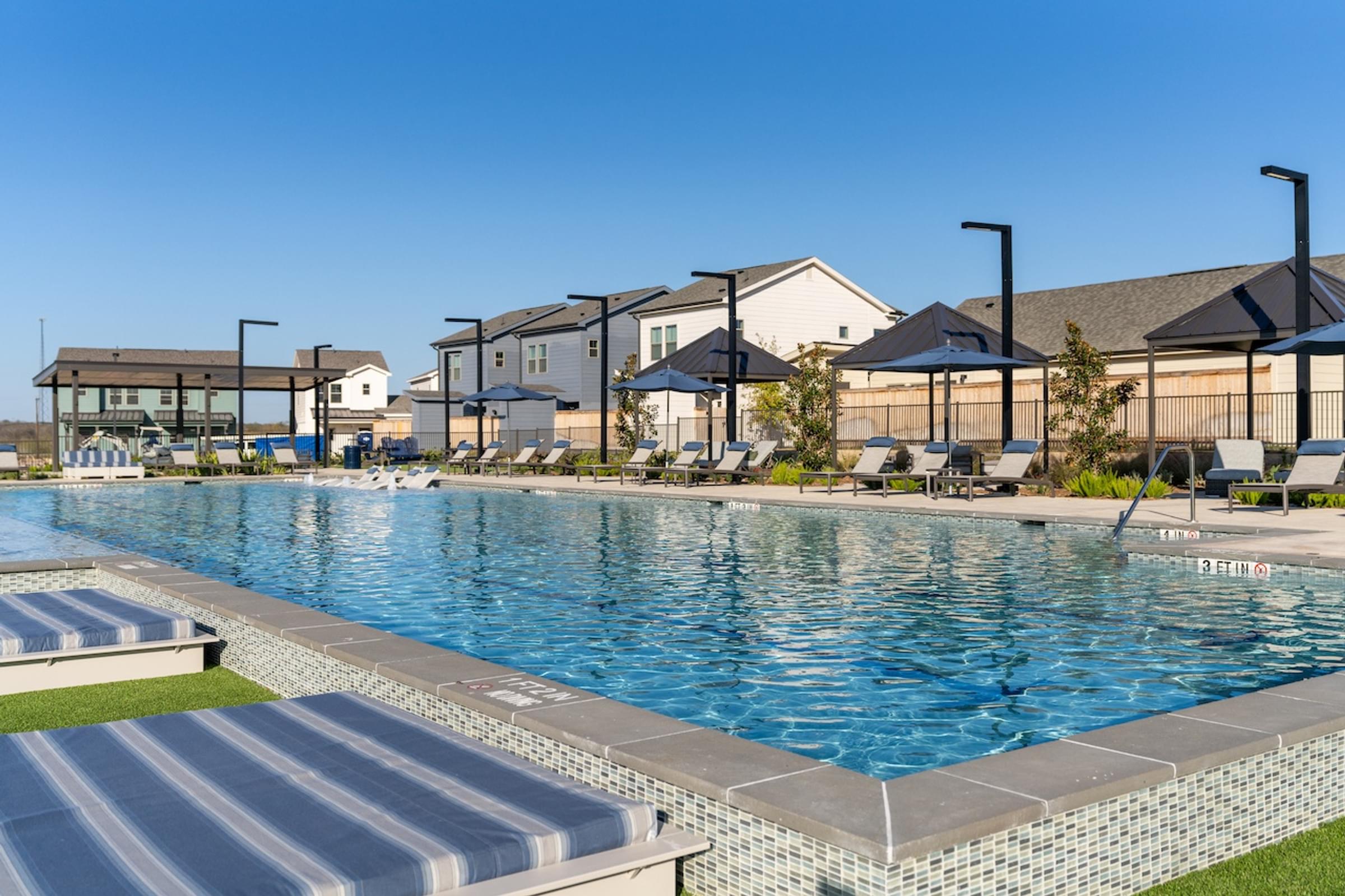 A large swimming pool with a blue tiled edge and a striped concrete ledge.