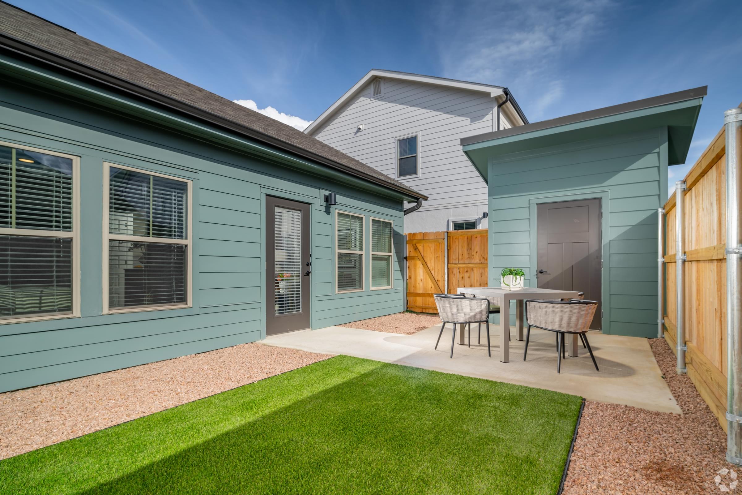 A house with a blue exterior and a patio with a table and chairs.