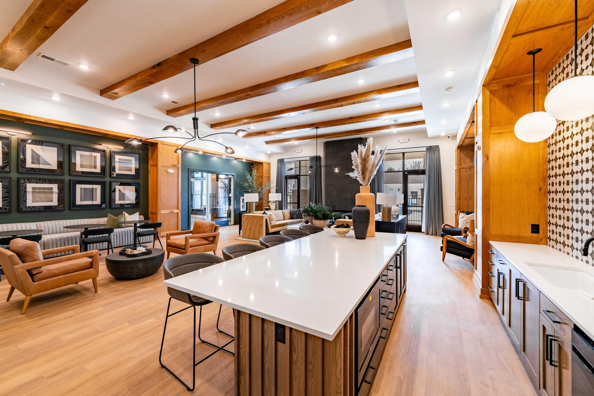 A modern kitchen with a long white island and wooden floors.