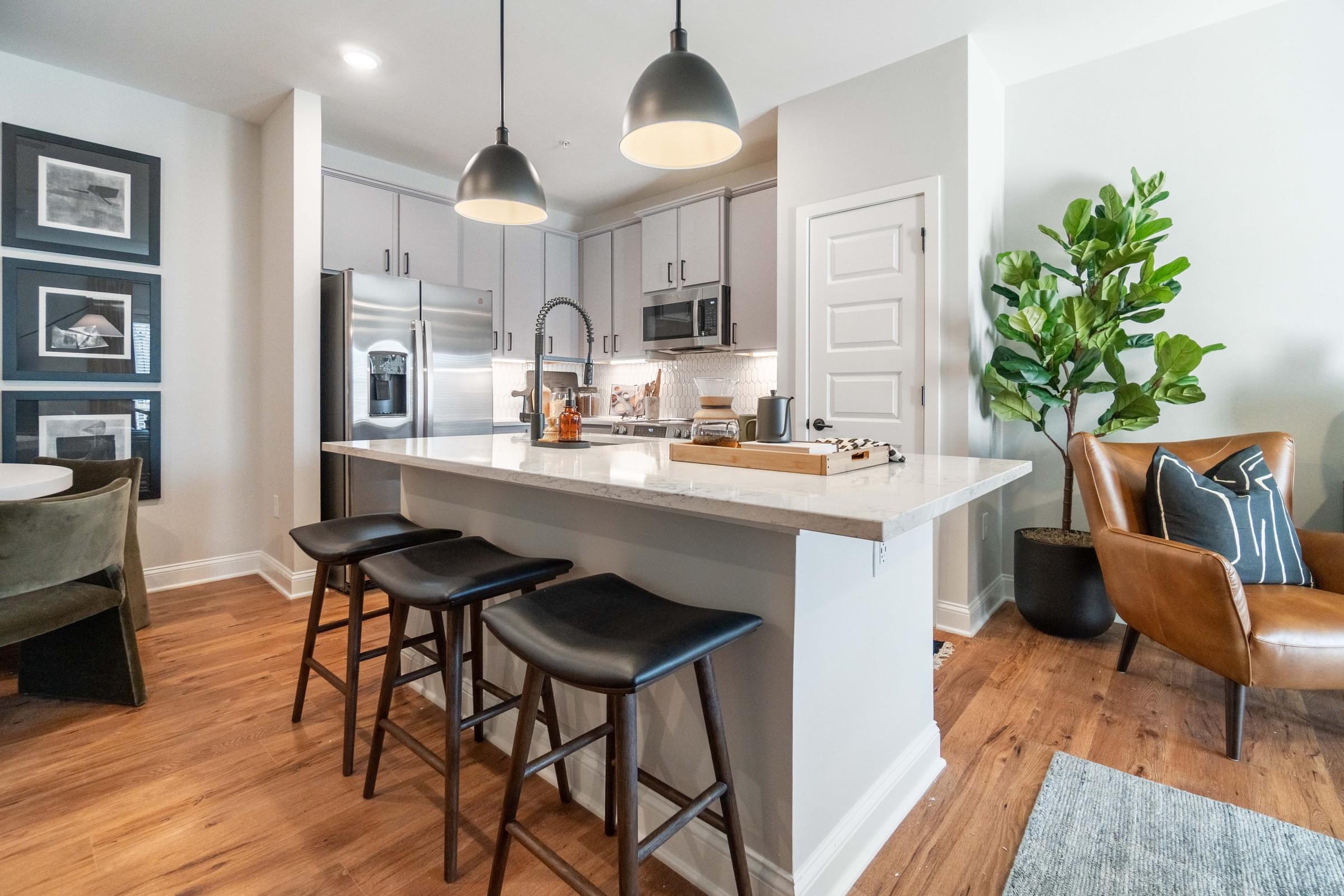 A kitchen with a white island and black stools.