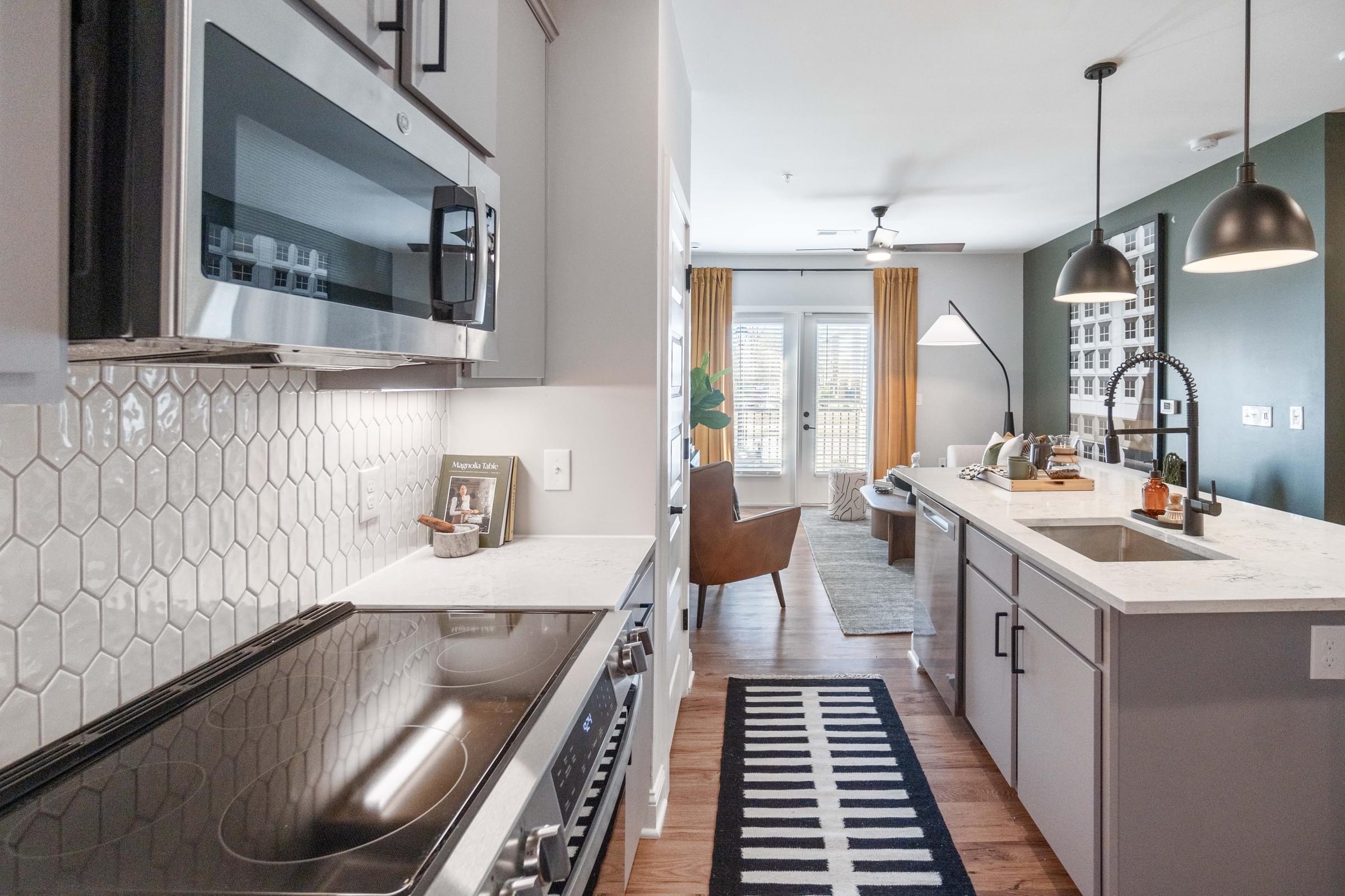 A modern kitchen with a black and white tiled backsplash and stainless steel appliances.