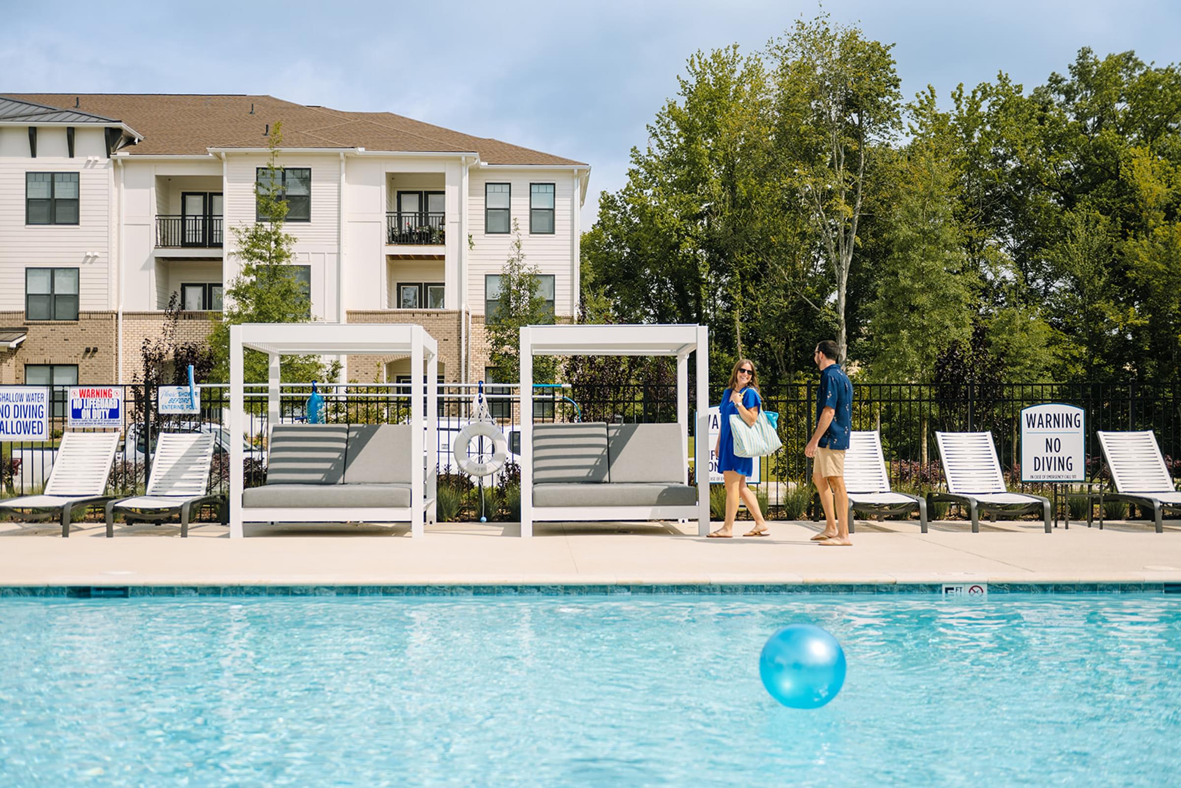 A swimming pool with a warning sign and two people standing by it.
