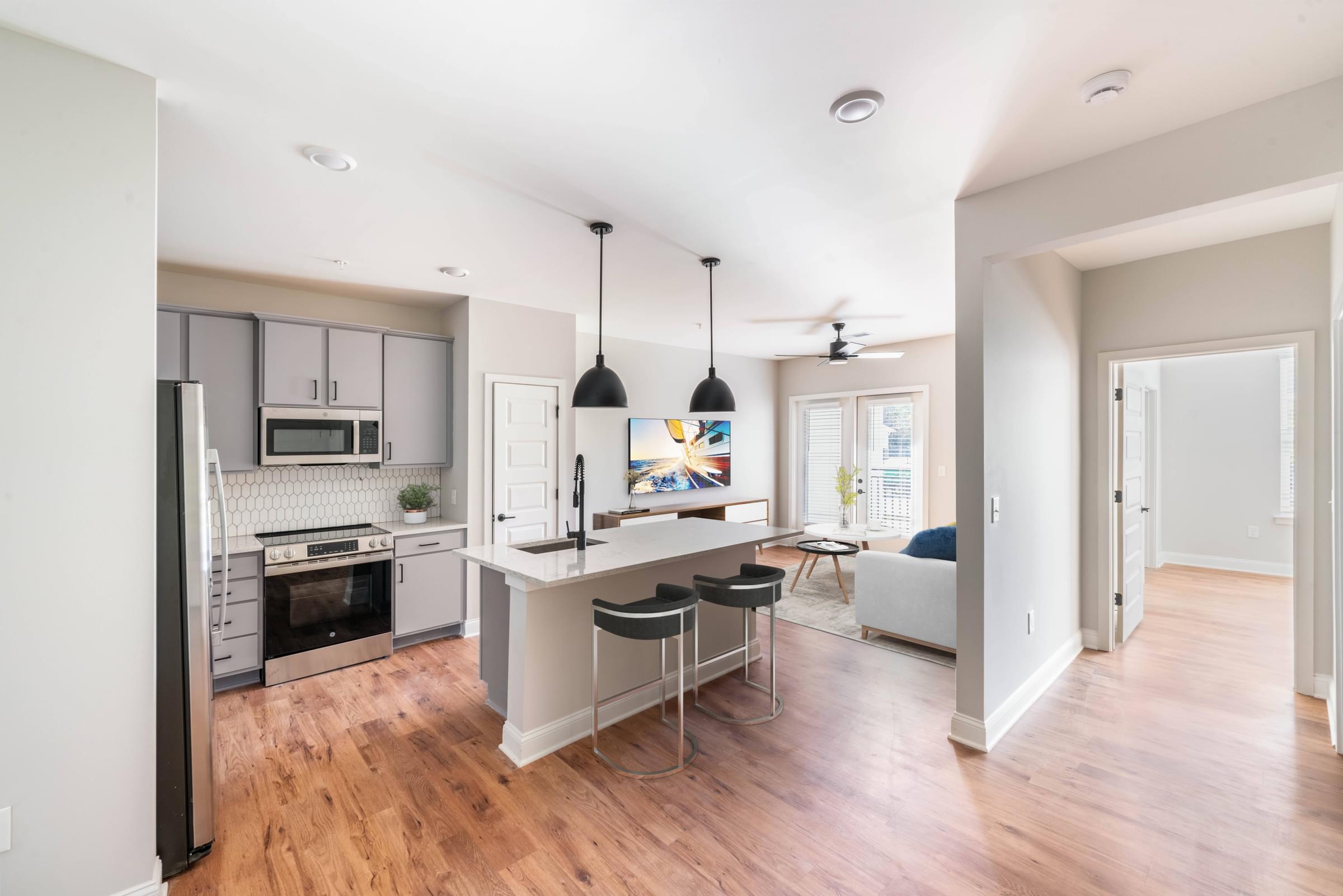 an open kitchen and living room with a large island with three stools