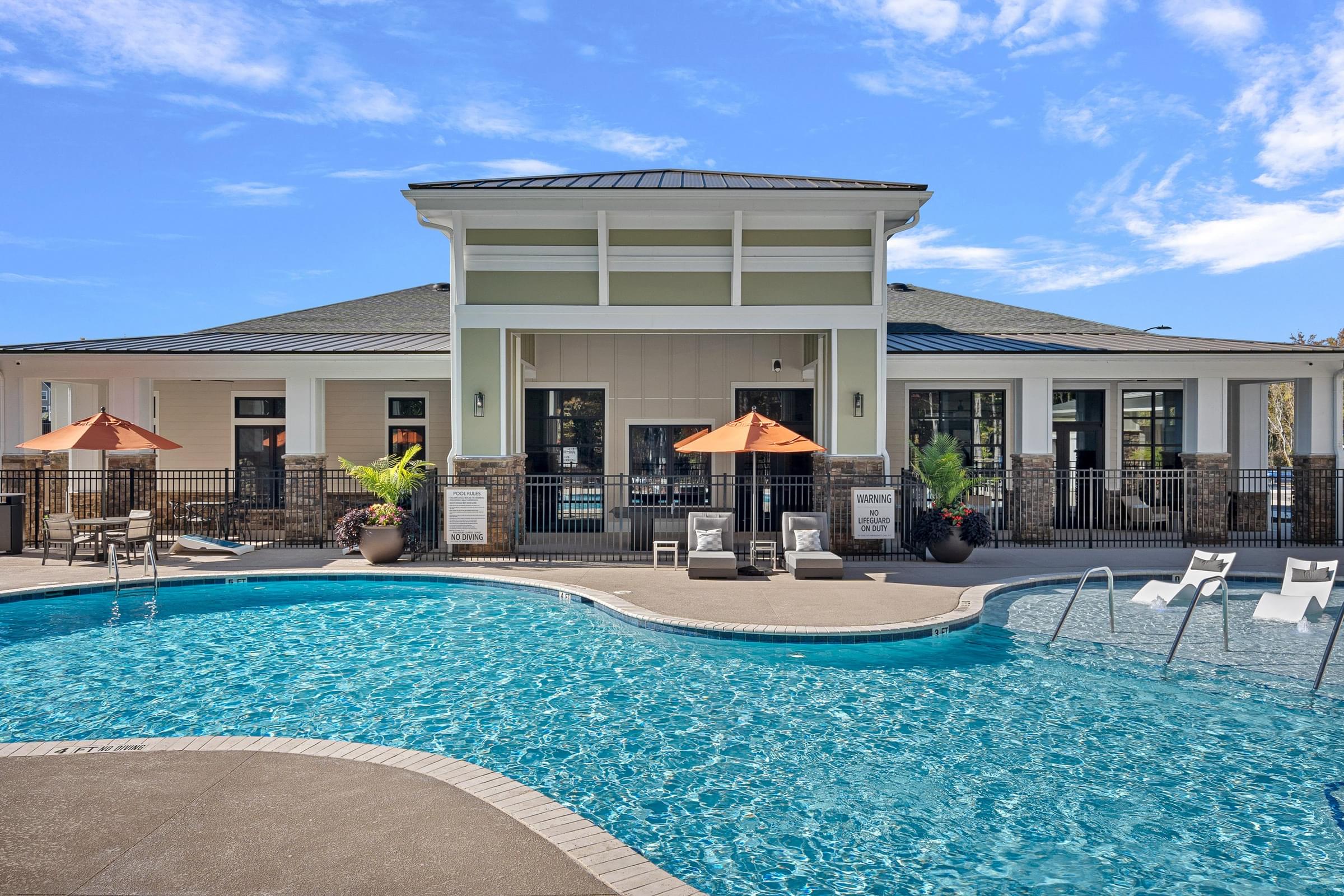 Outdoor Swimming Pool with Loungers Surrounding and Umbrellas Open.