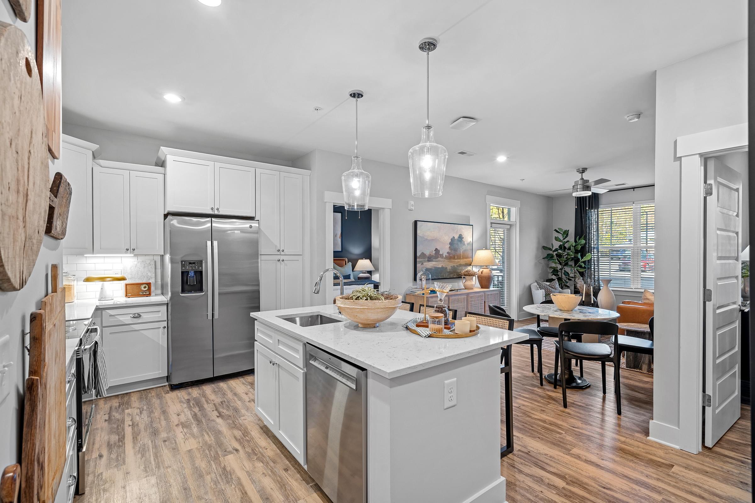 A modern kitchen with a large island and stainless steel appliances leading into the living room