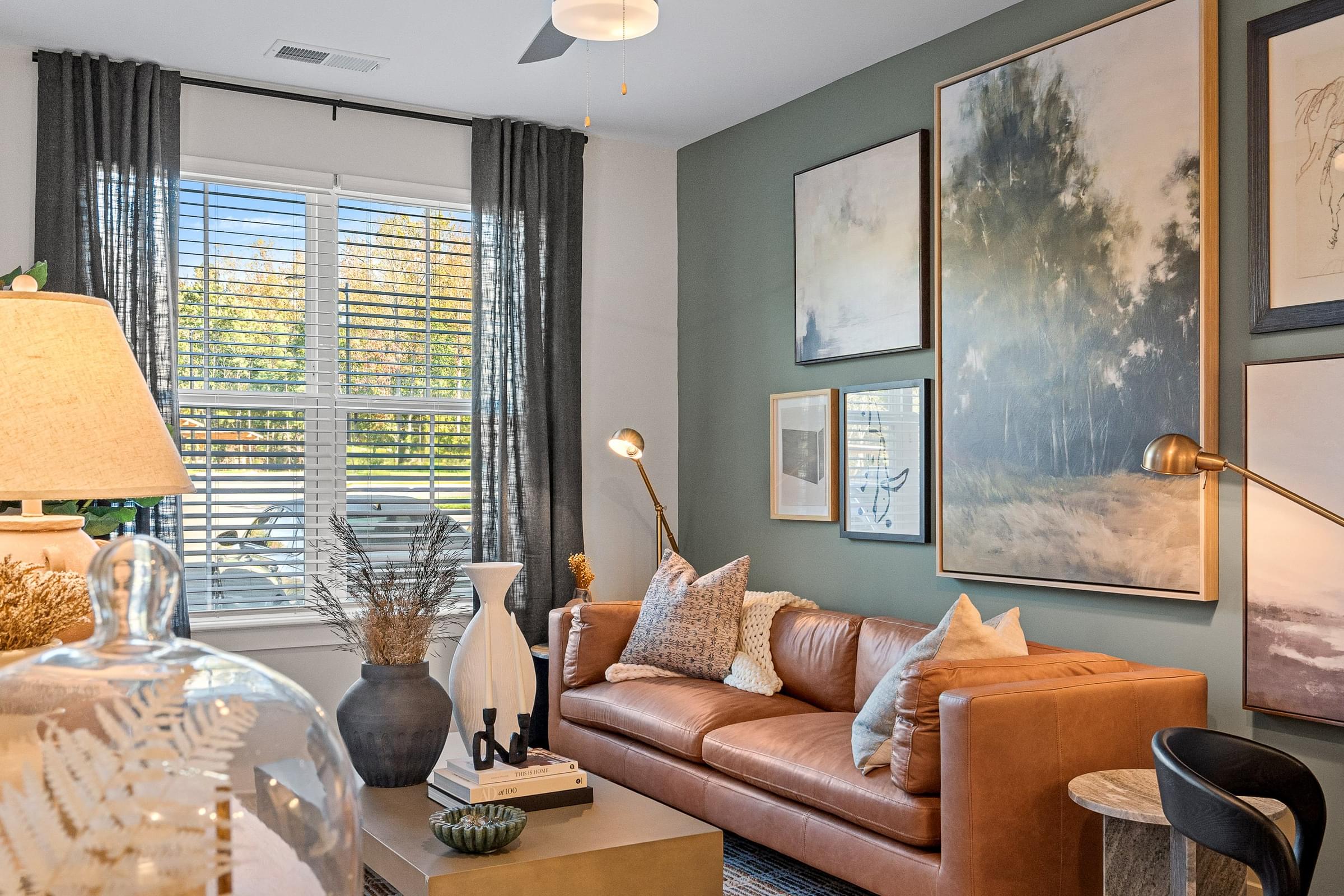 A Living Room with a Brown Couch and a Painting on the Wall with Decor on the Coffee Table.