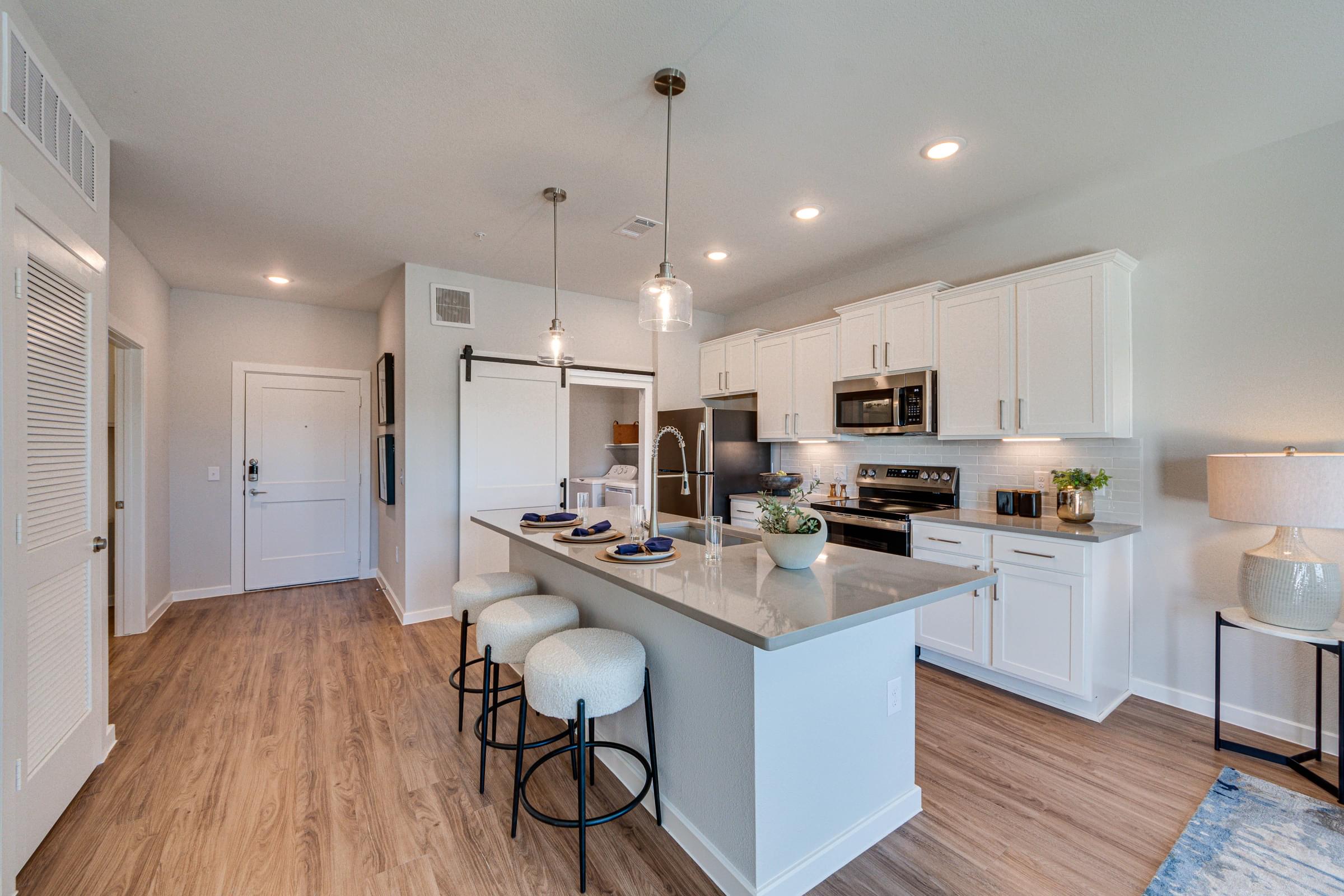 Spacious Kitchen with White Cabinets and a Large Island with Barstools