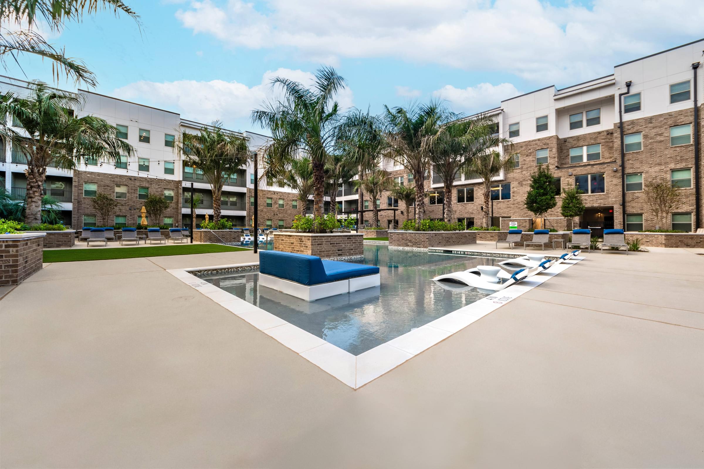 A modern courtyard with a pool surrounded by buildings and palm trees.
