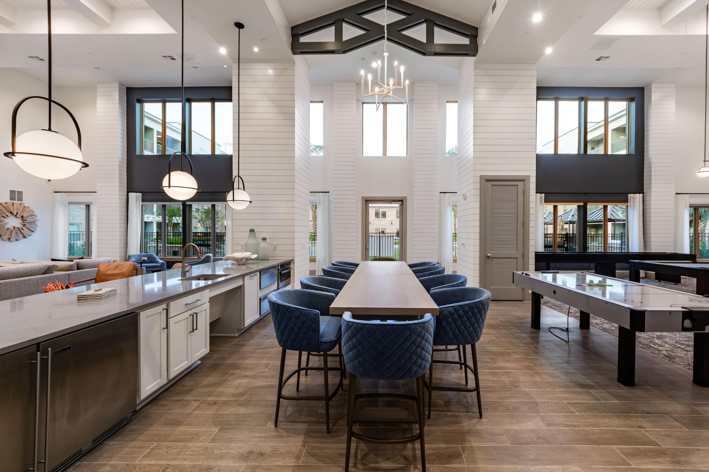 A modern kitchen with a large island and blue chairs.