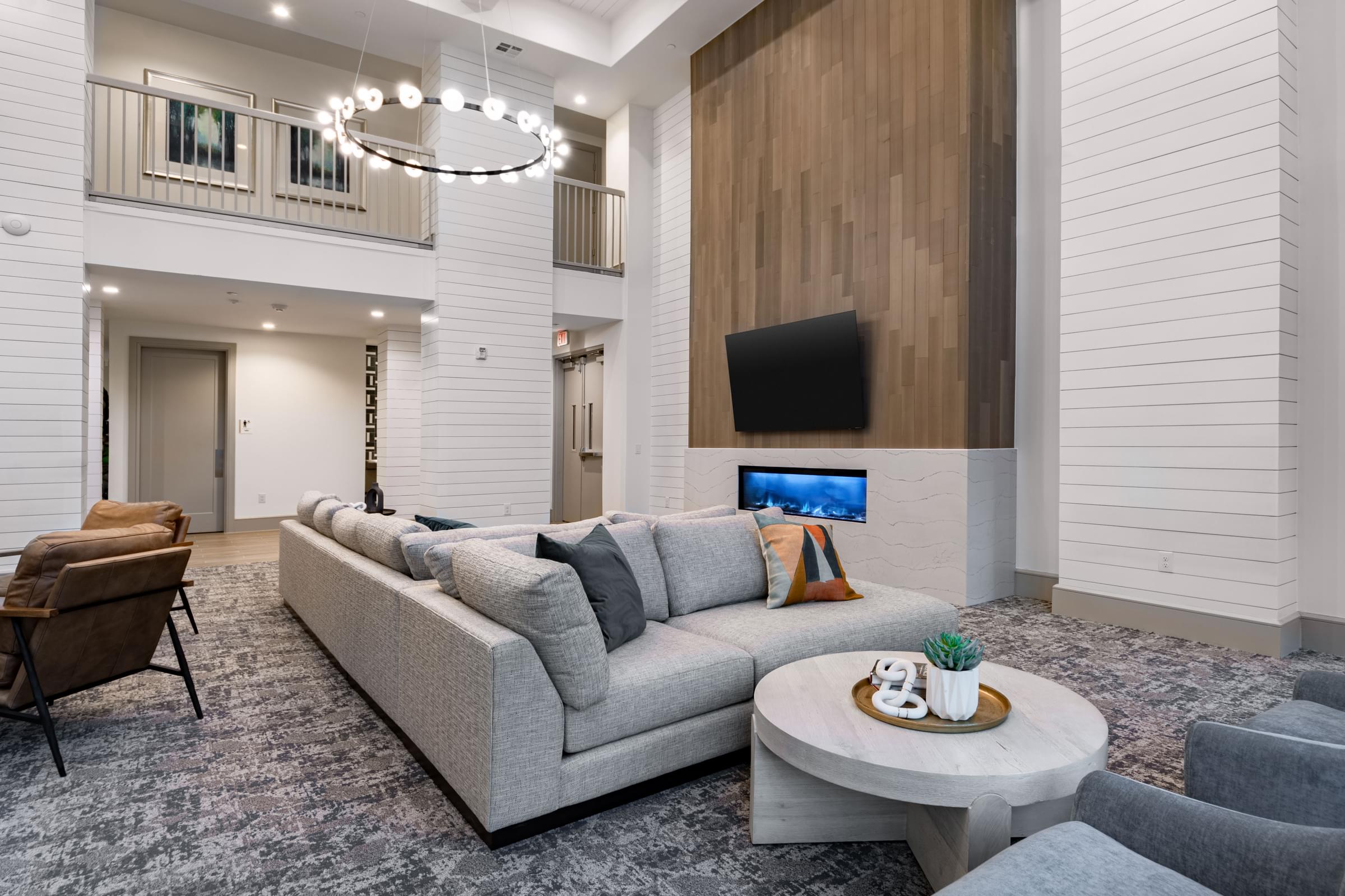 A modern living room with a grey sofa and a wooden wall.