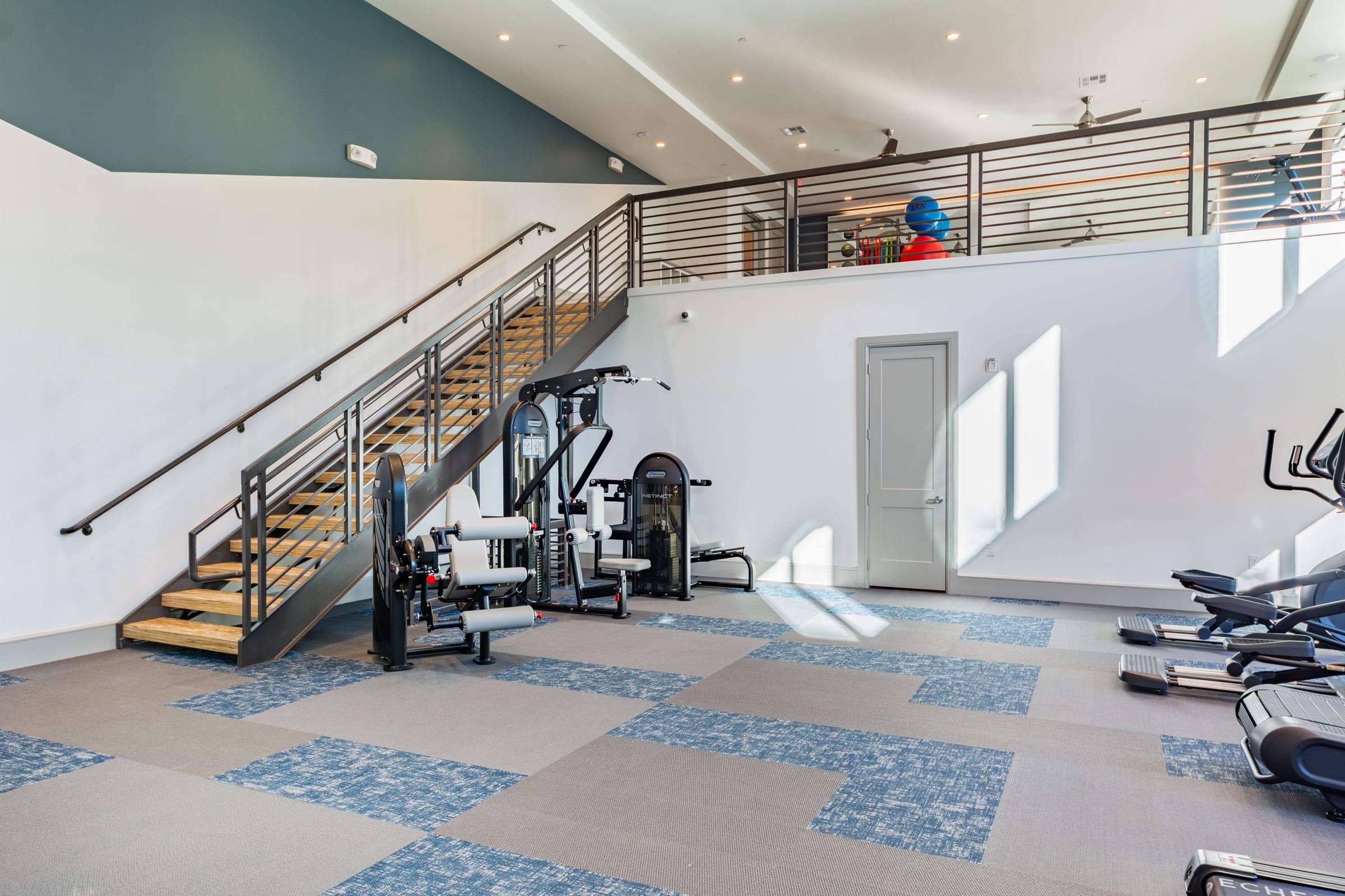 a gym with stairs and exercise equipment and a person on the stairs