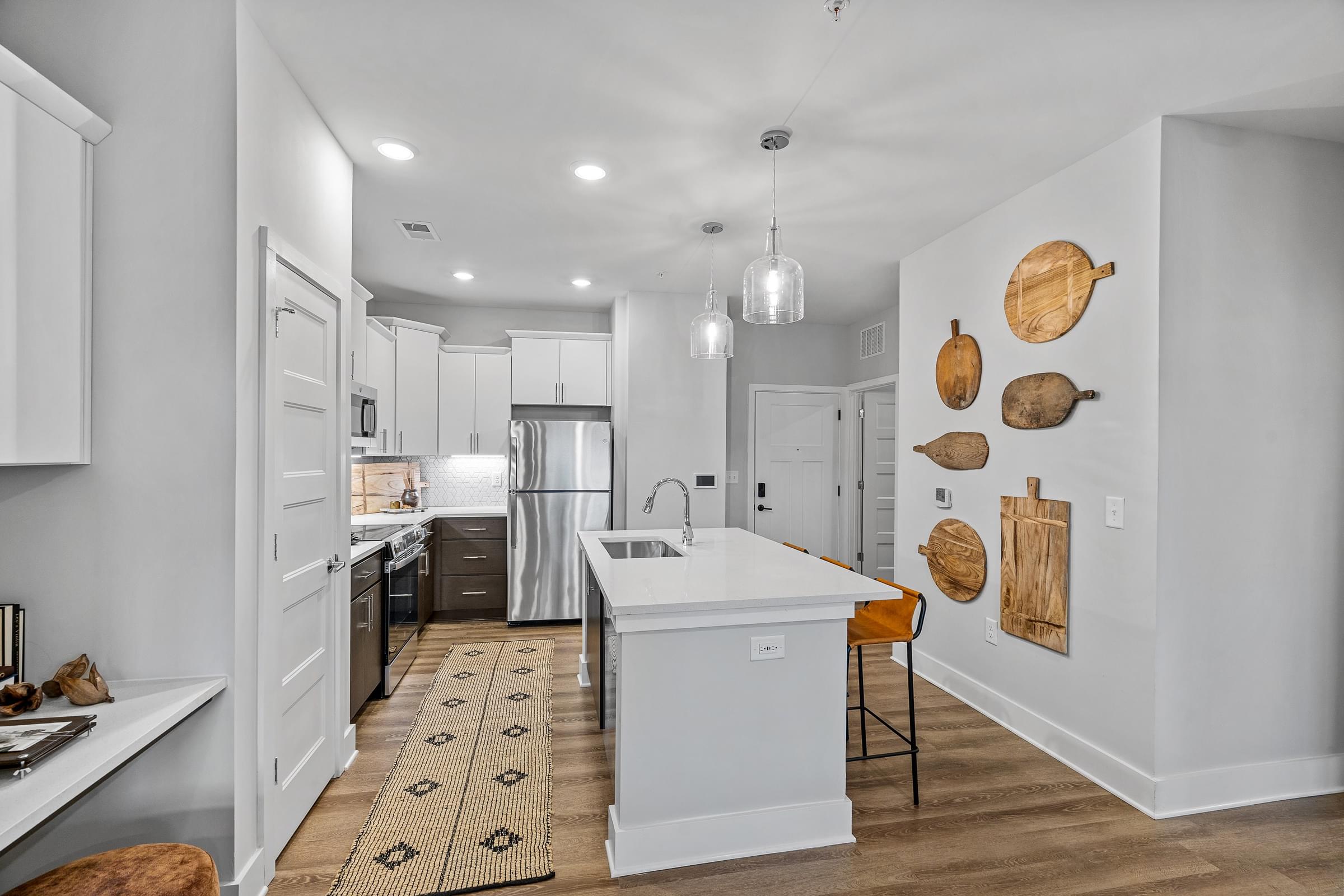 A modern kitchen with a white island and wooden wall decor.