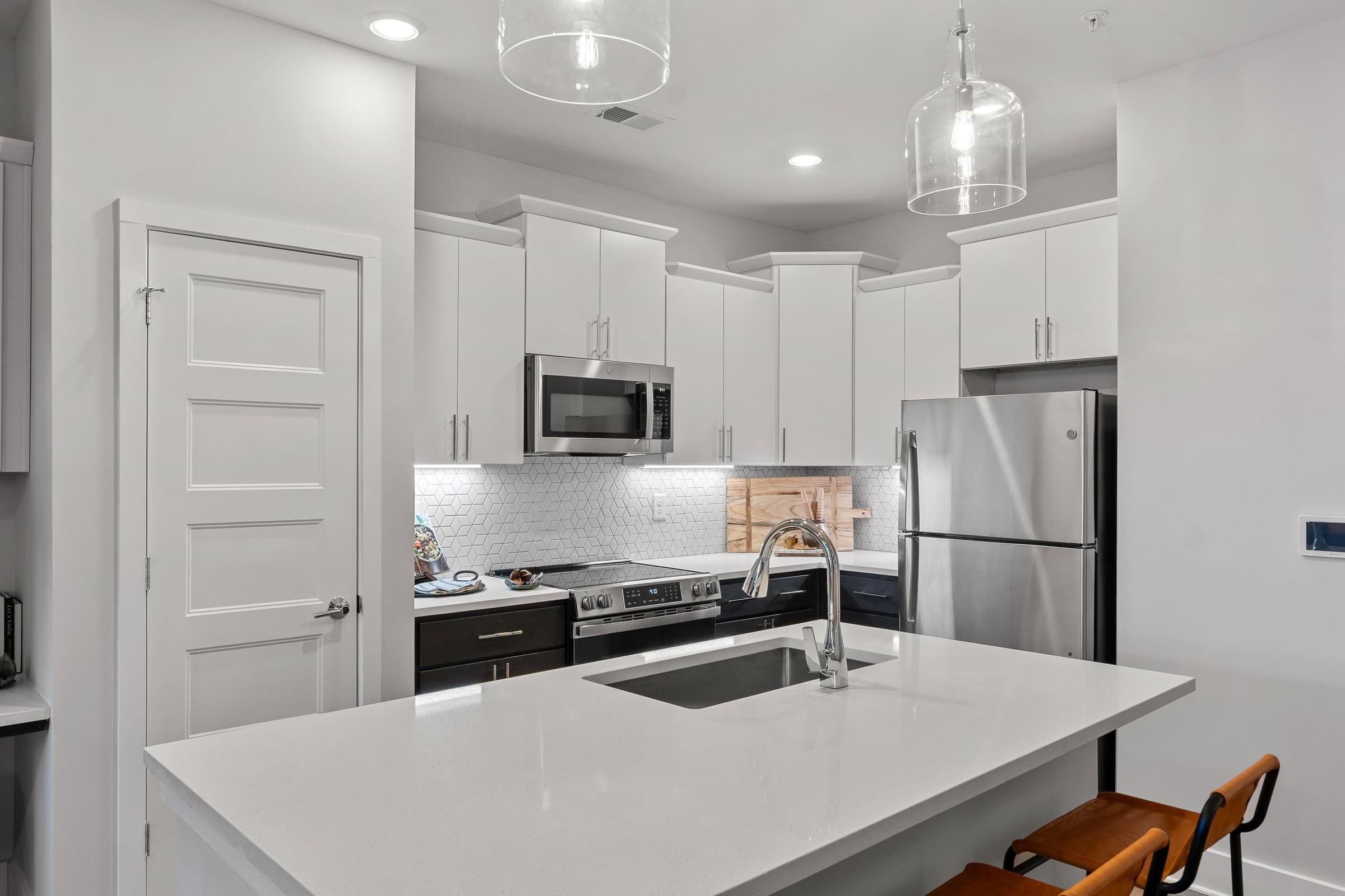 A modern kitchen with a white countertop and stainless steel appliances.